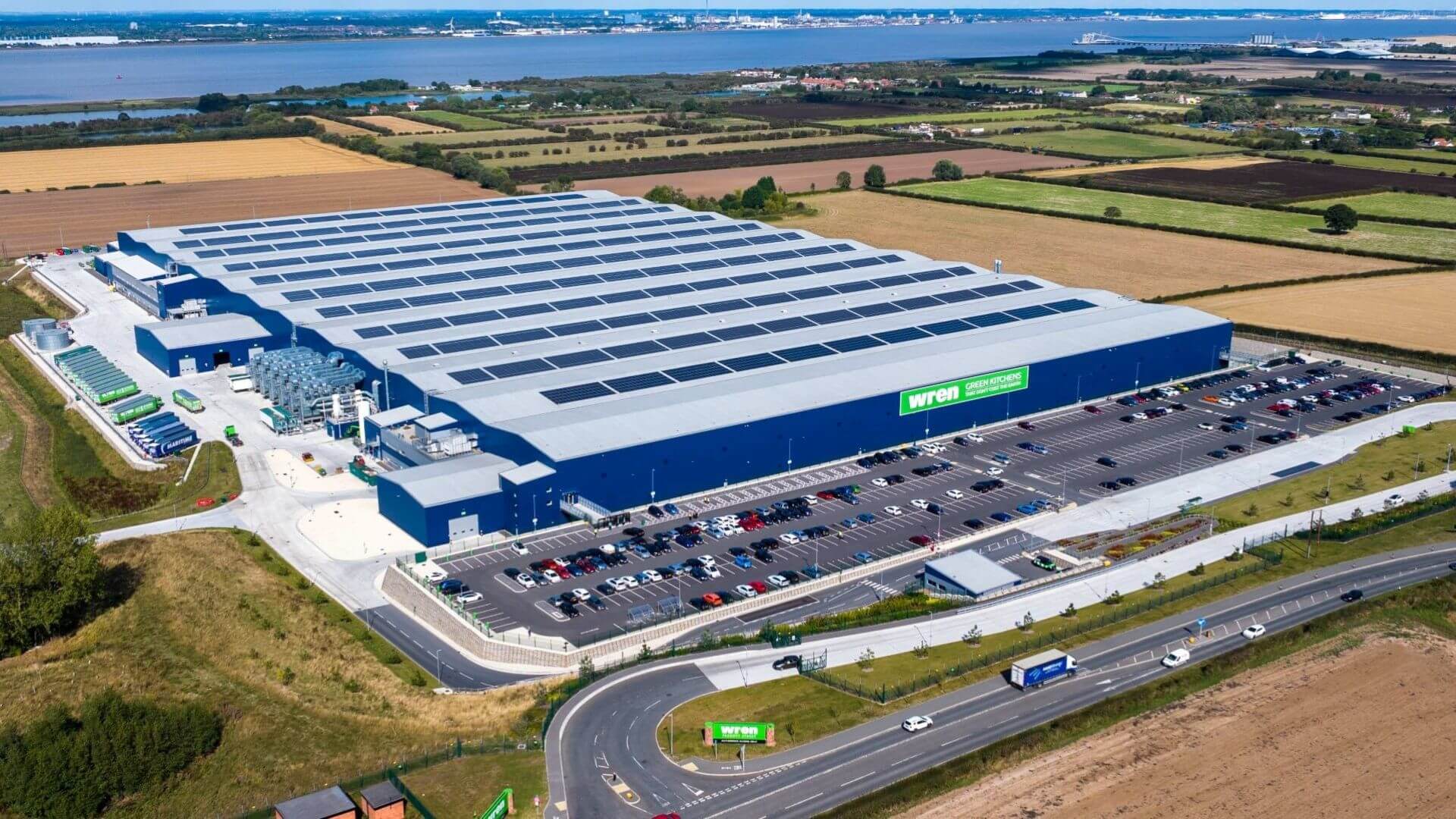 Aerial view over large warehouse style building with zig zag roof covered with solar panels