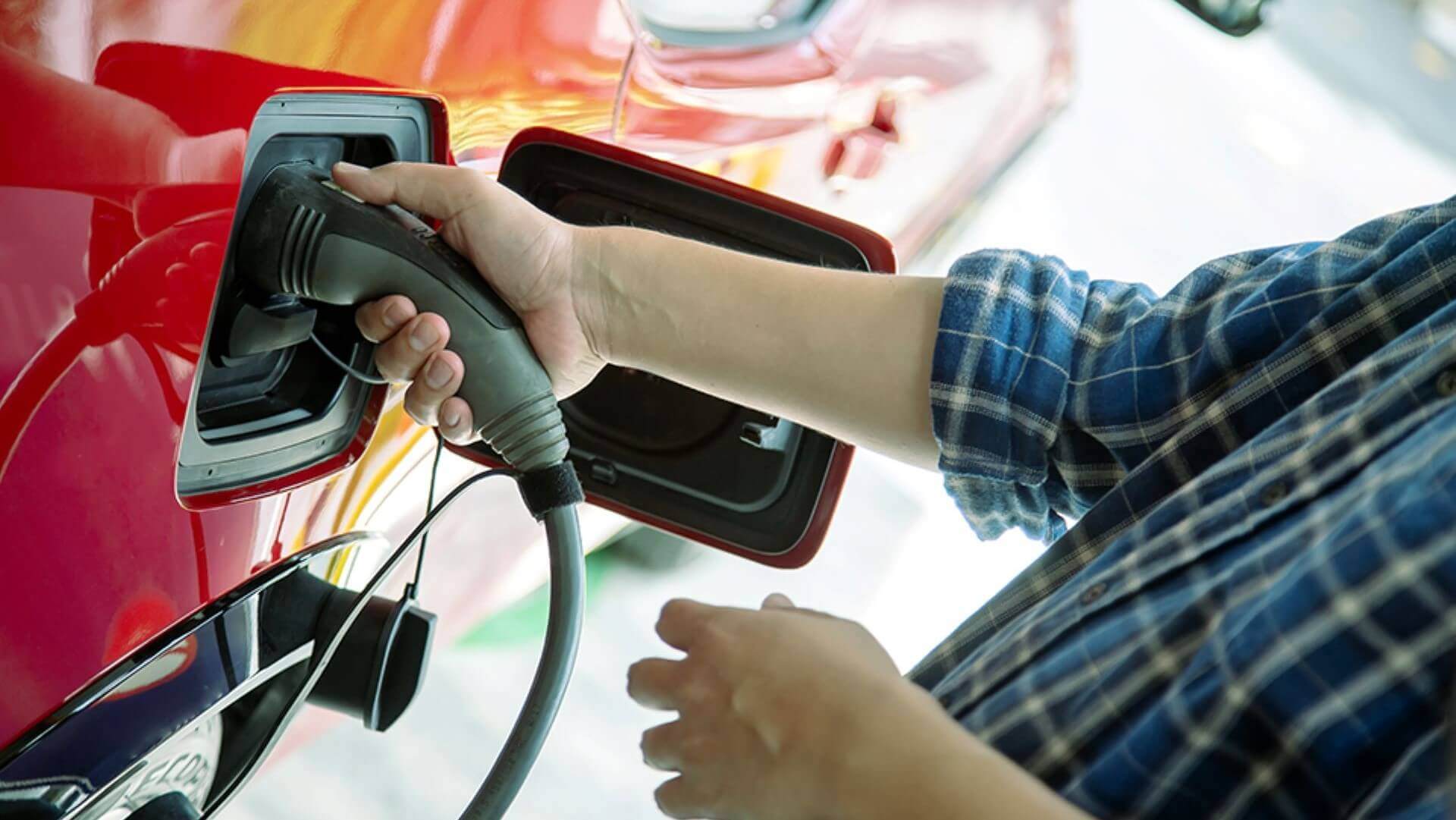 close up of person connecting electric vehicle to charging installation