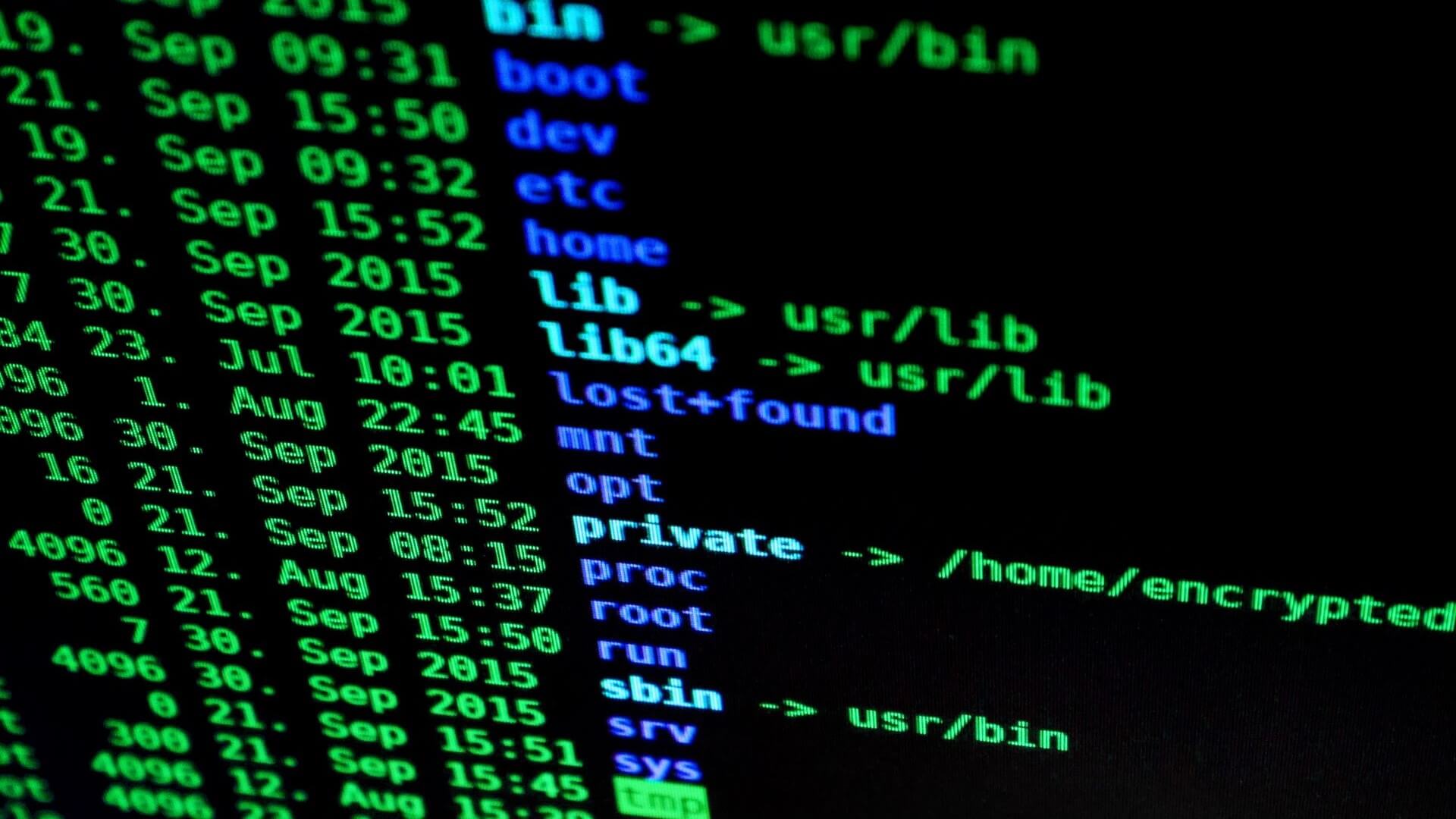 Dark computer screen with green and blue computer coding across it