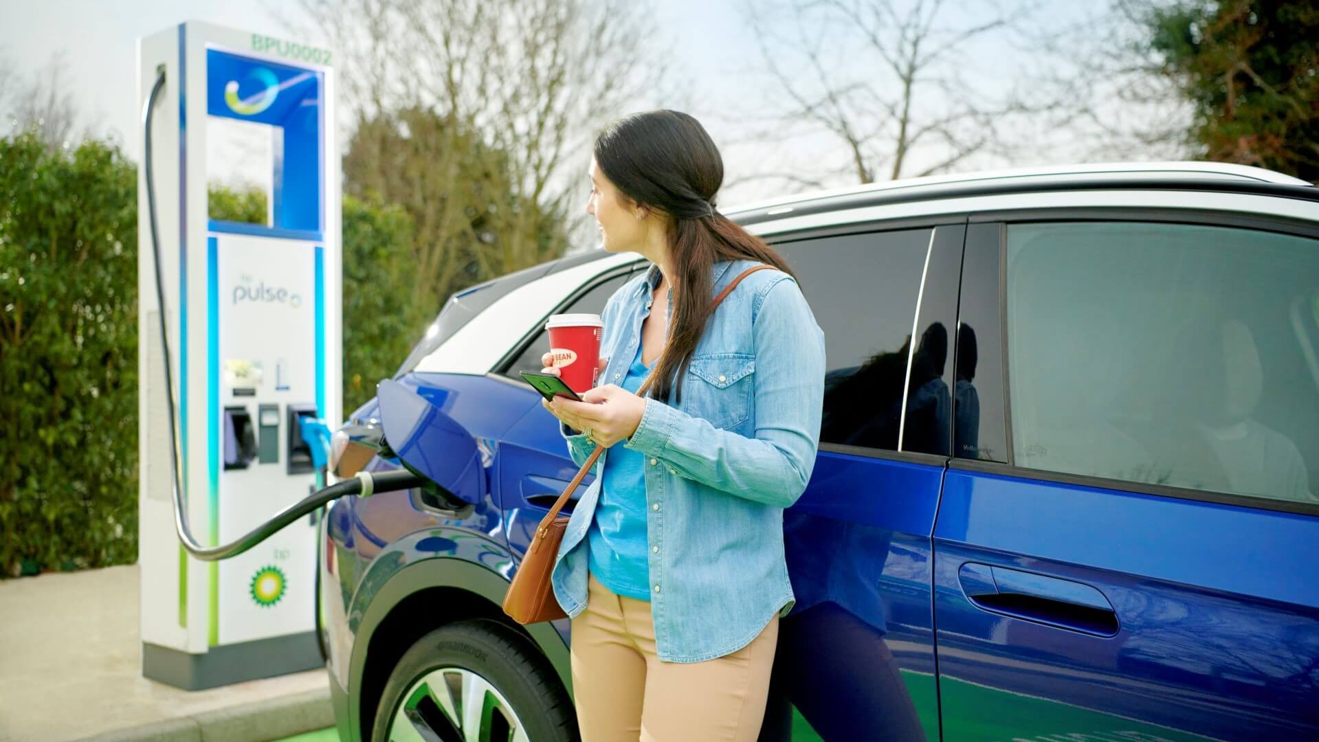 Woman waiting by car charging at BP EV point
