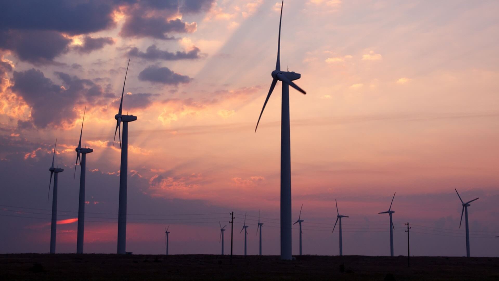 Lines of onshore wind turbines with sunset in background