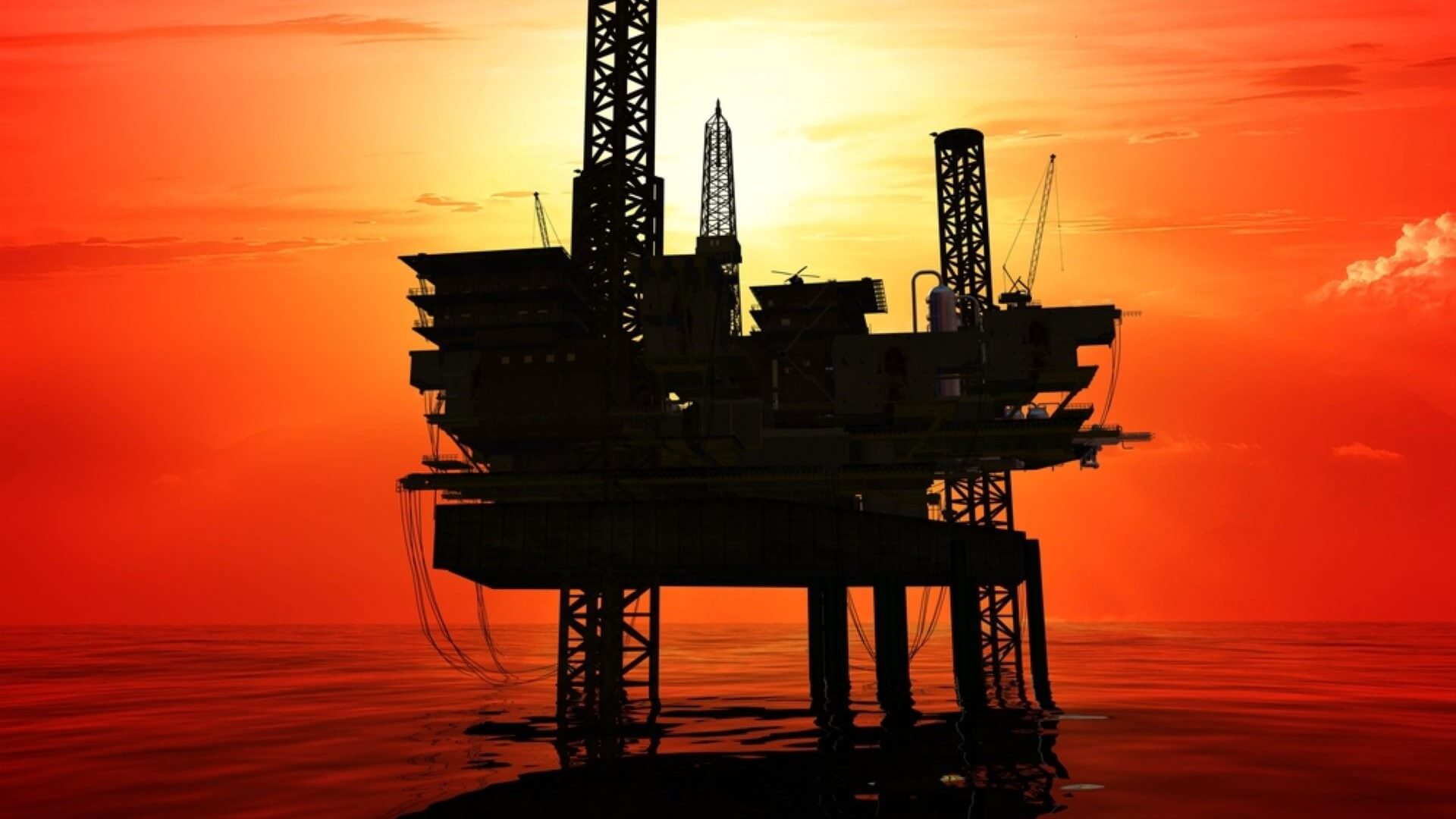 Oil rig silhouette set against orange sunset