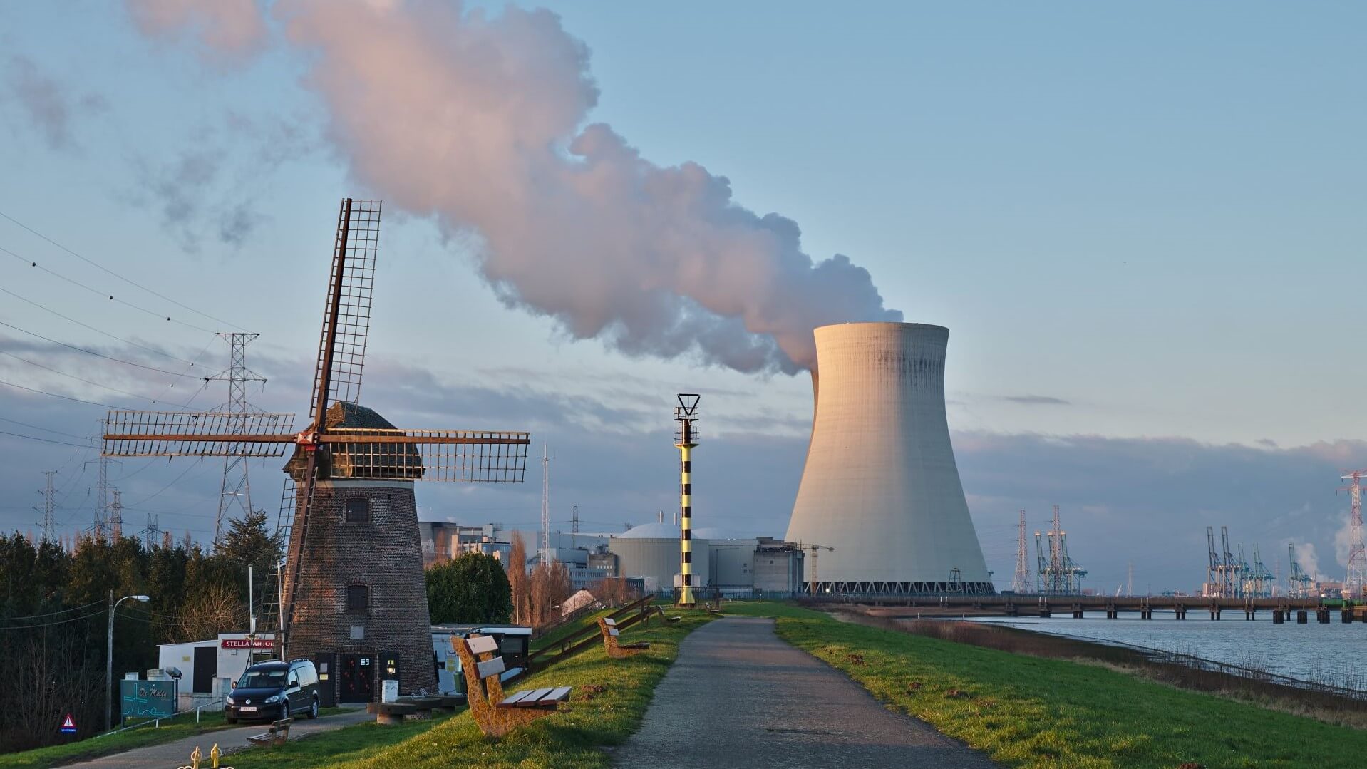 Cooling tower of Belgian Doel nuclear power plant with windmill in foreground