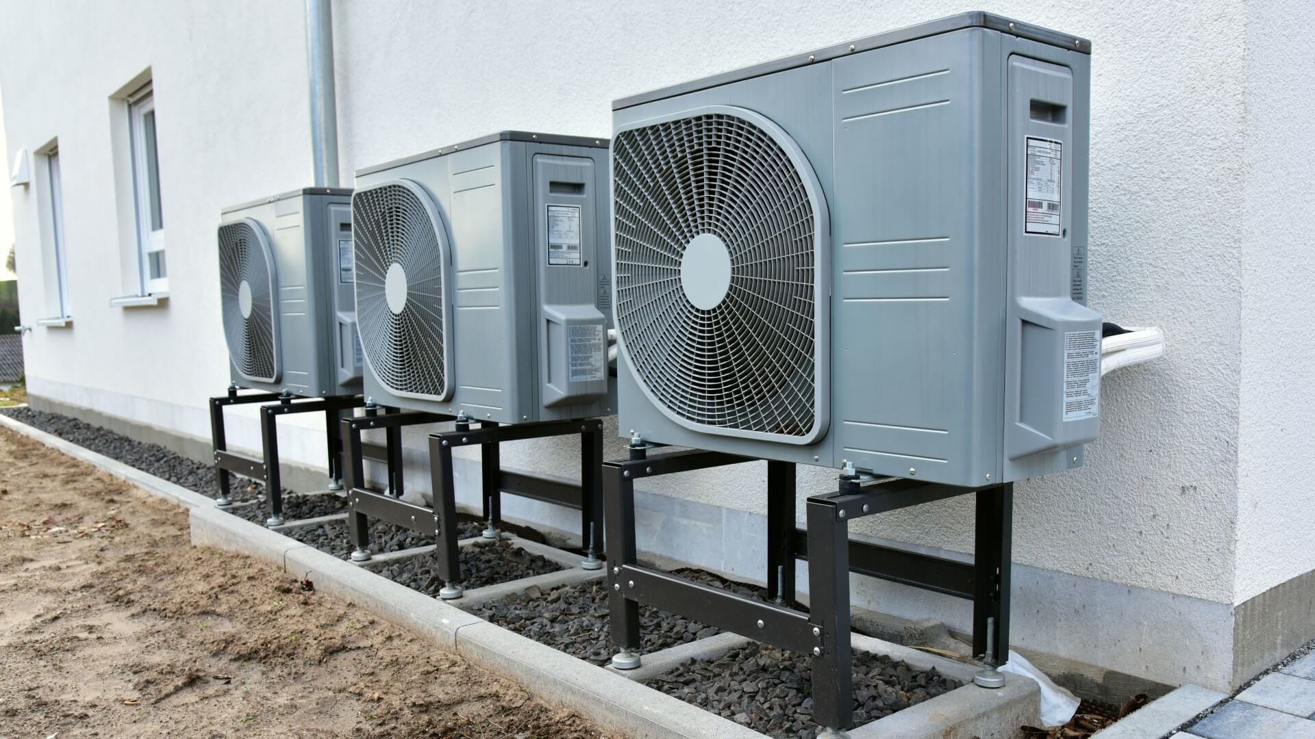 Close up of air-to-heat pump on outside wall of building