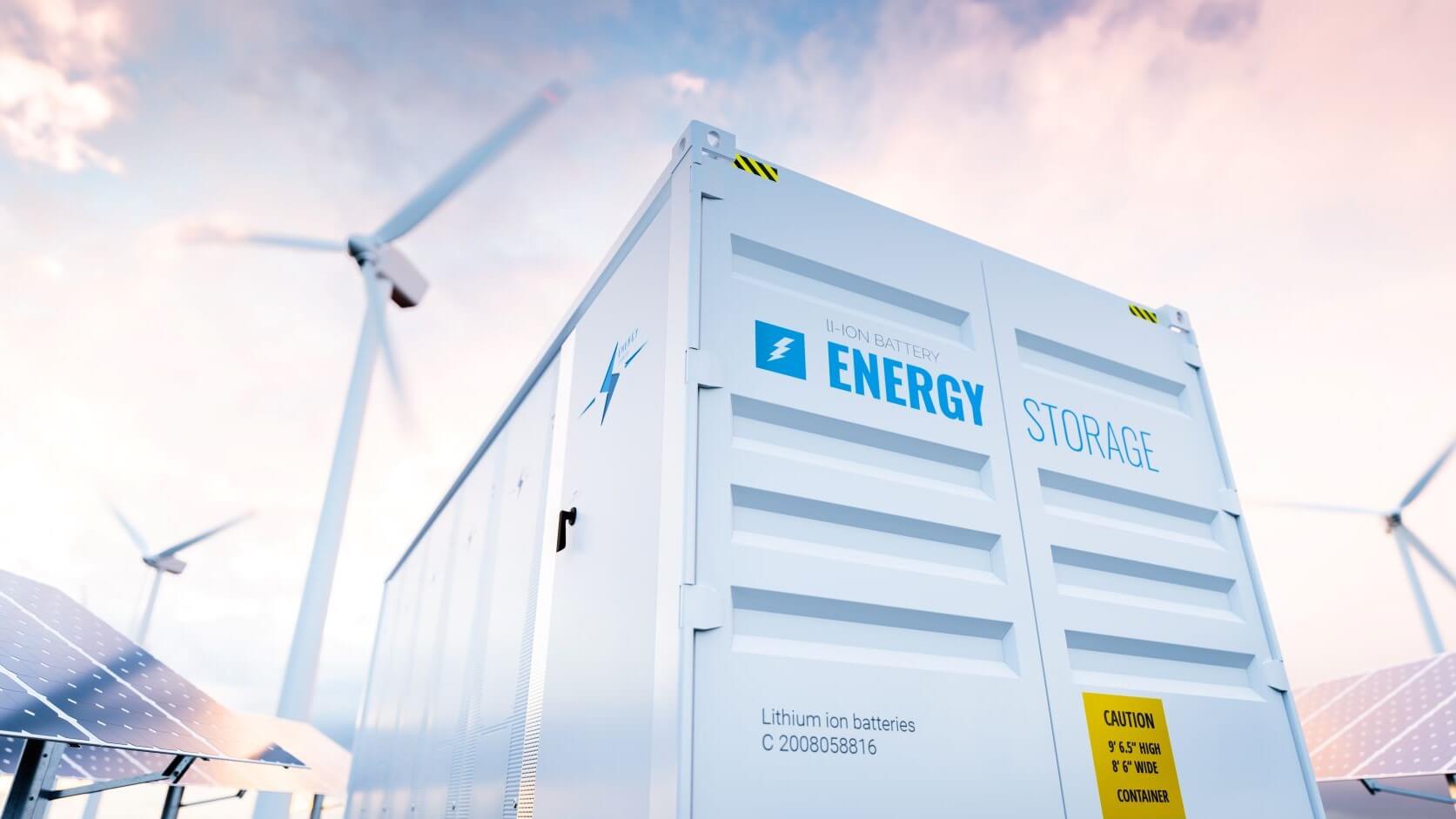 White energy storage container with solar panels to the left and wind turbines between 