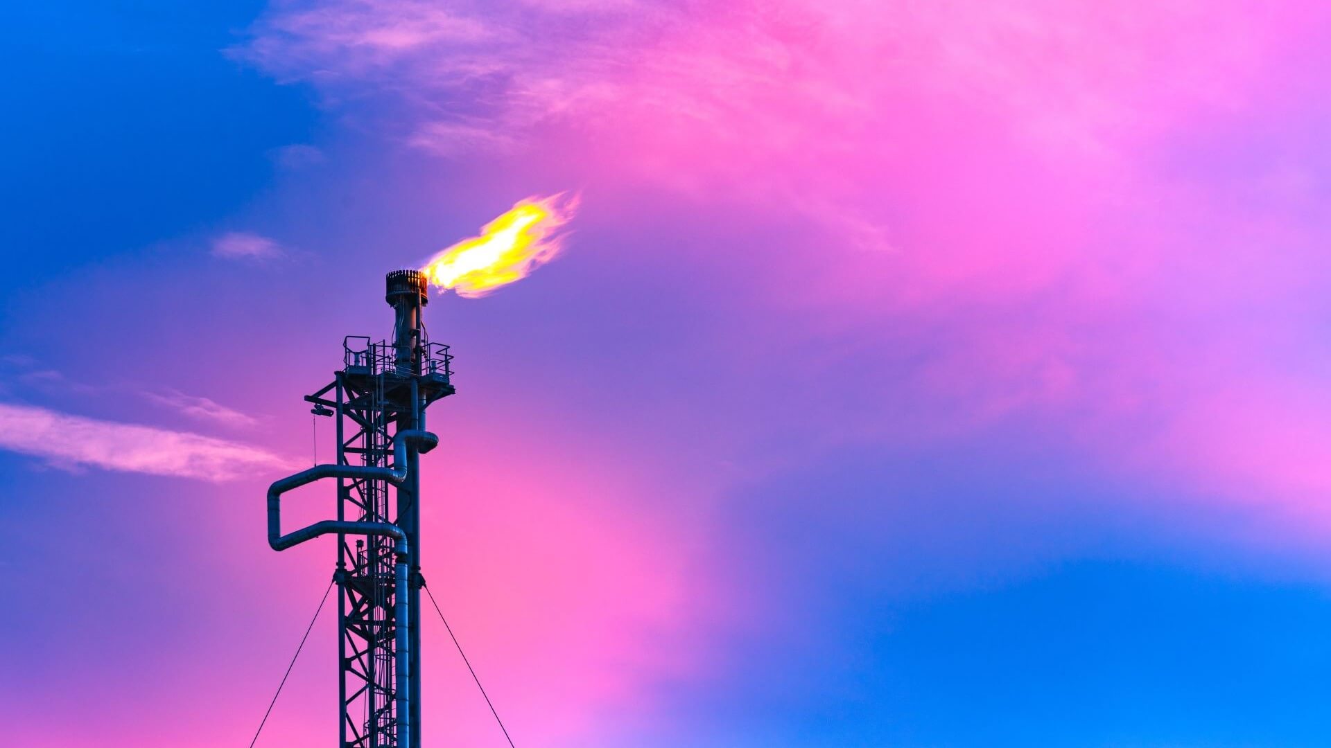 Close up of gas flare set against dramatic blue and pink sky