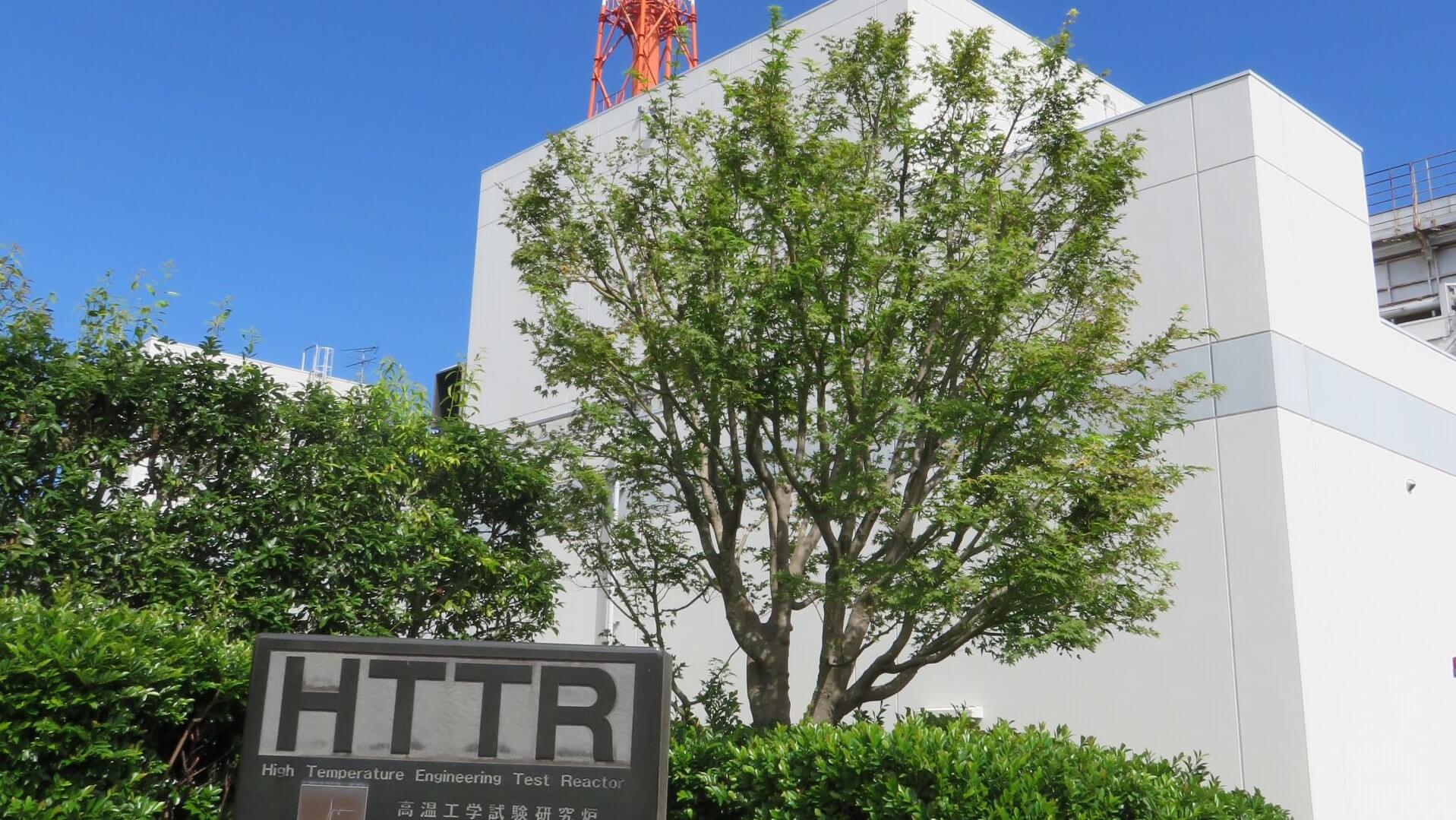 Green leafy trees in front of building housing a high-temperature engineering test reactor in Japan