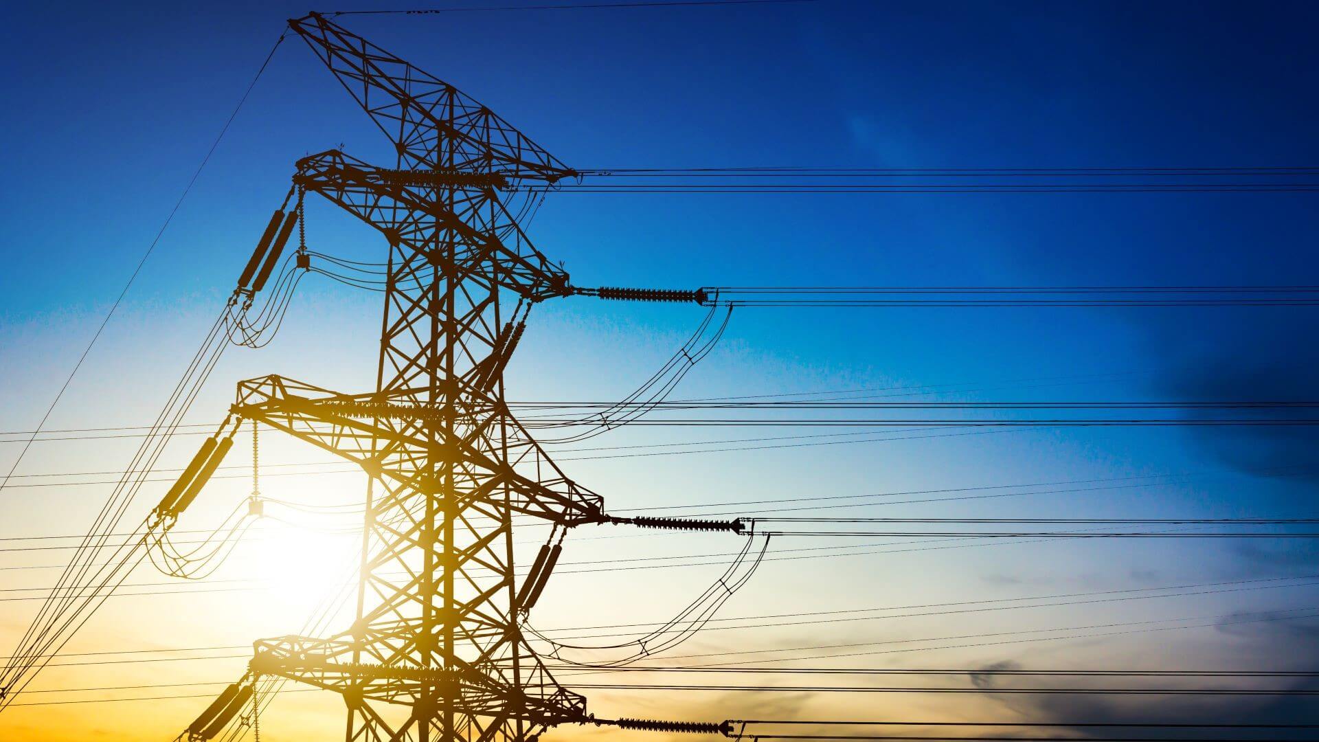 Electricity pylon in foreground with dramatic blue and yellow sky behind