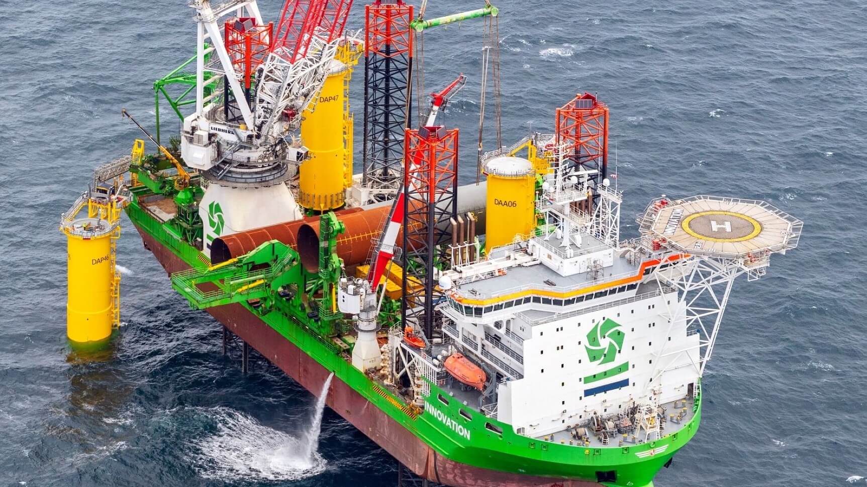 Crane on vessel at sea lifting wind turbine foundation into position