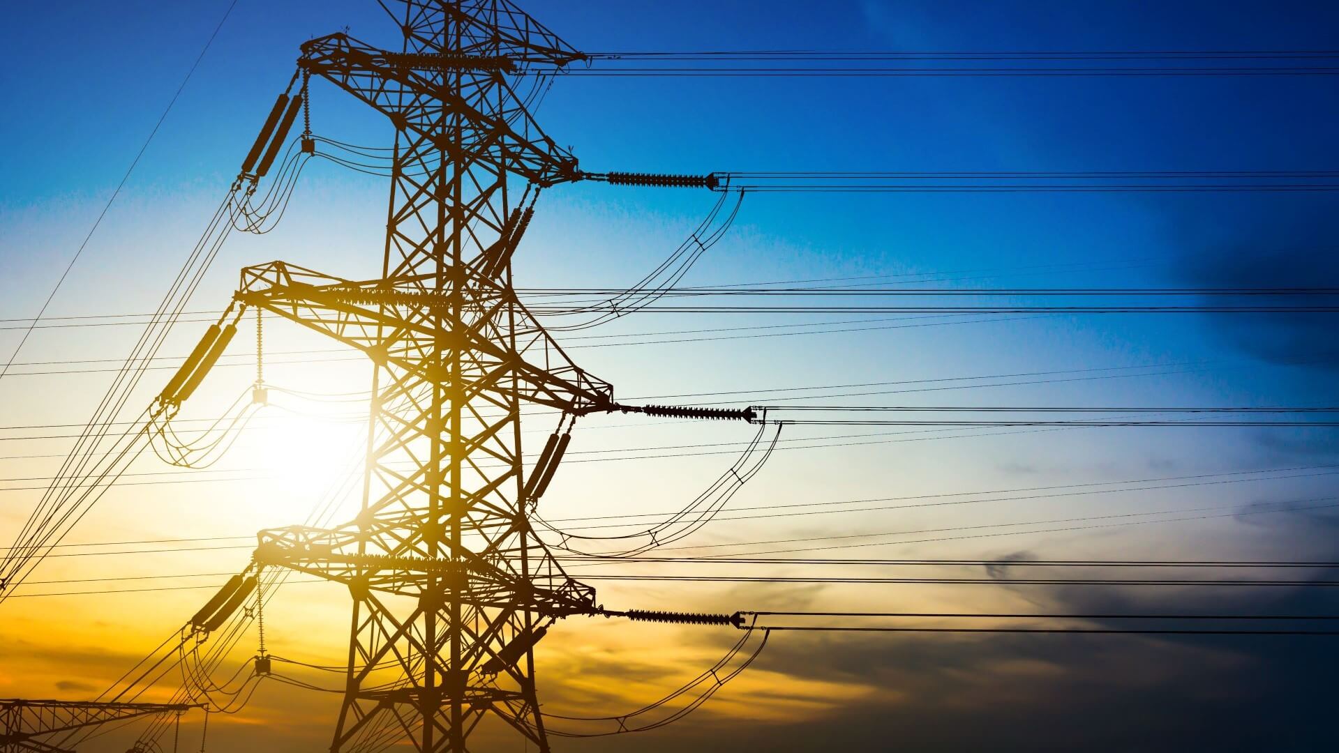 Electricity pylon in foreground with blue and yellow sky behind