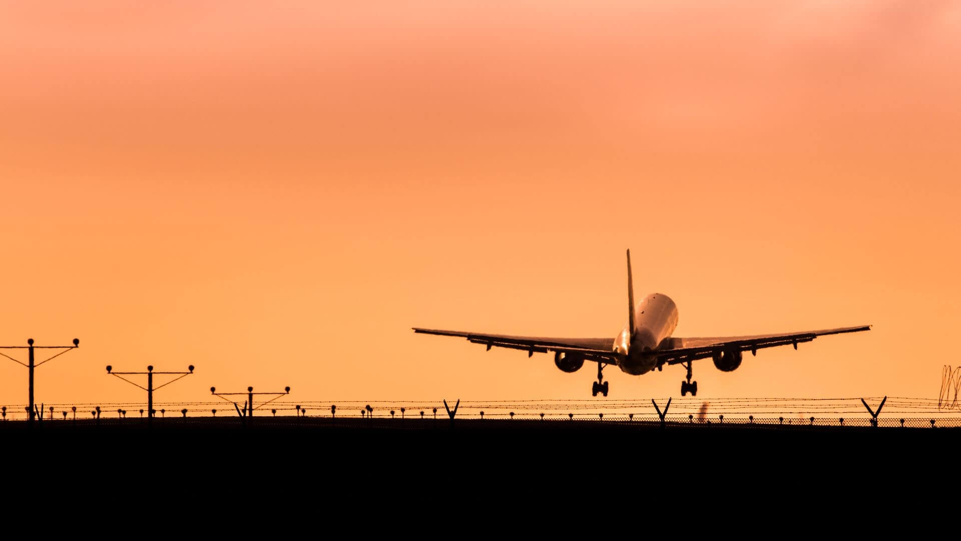 Plane taking off from runway at sunset