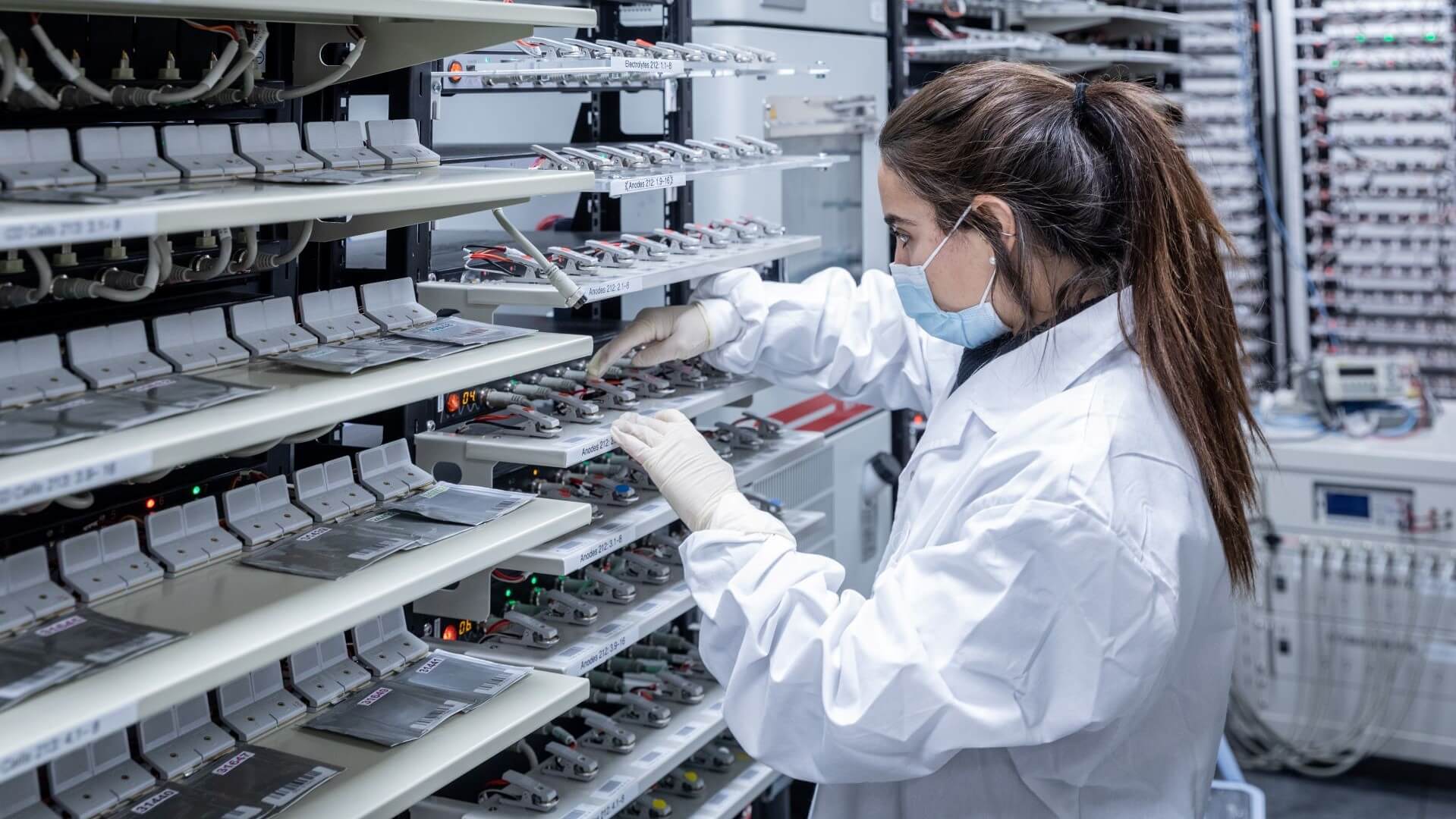 Female lab technician in front of row upon row of solid state batteries