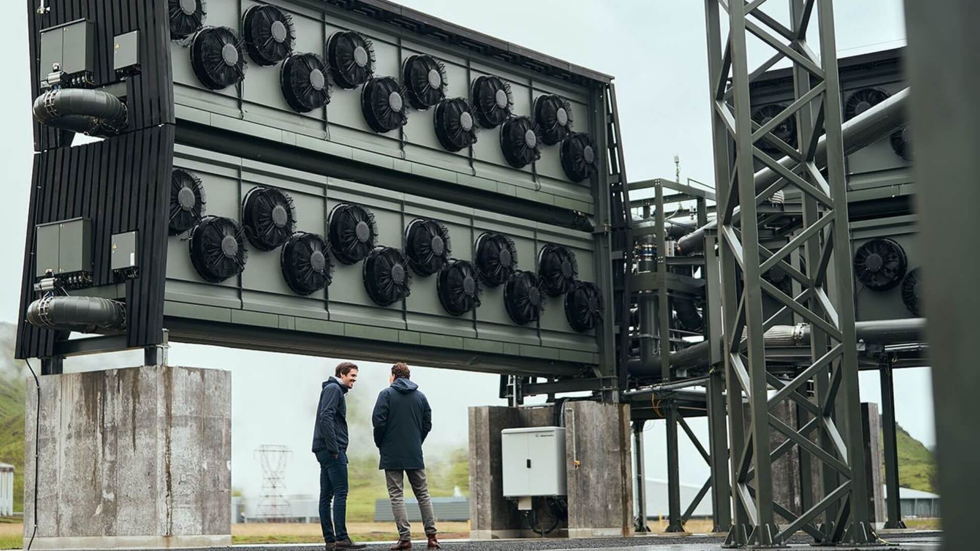 Two men stand in front of a Climeworks DAC facility