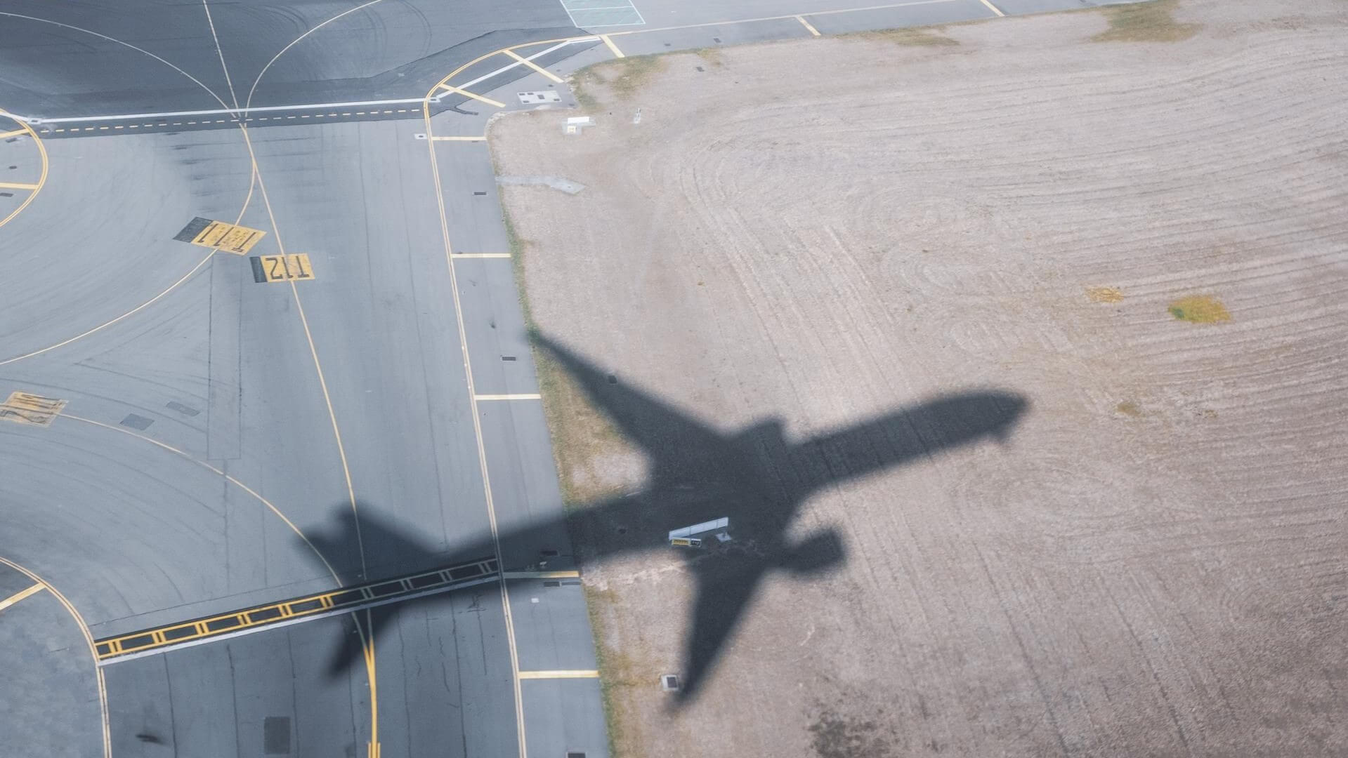 Shadow of plane flying over airport runway