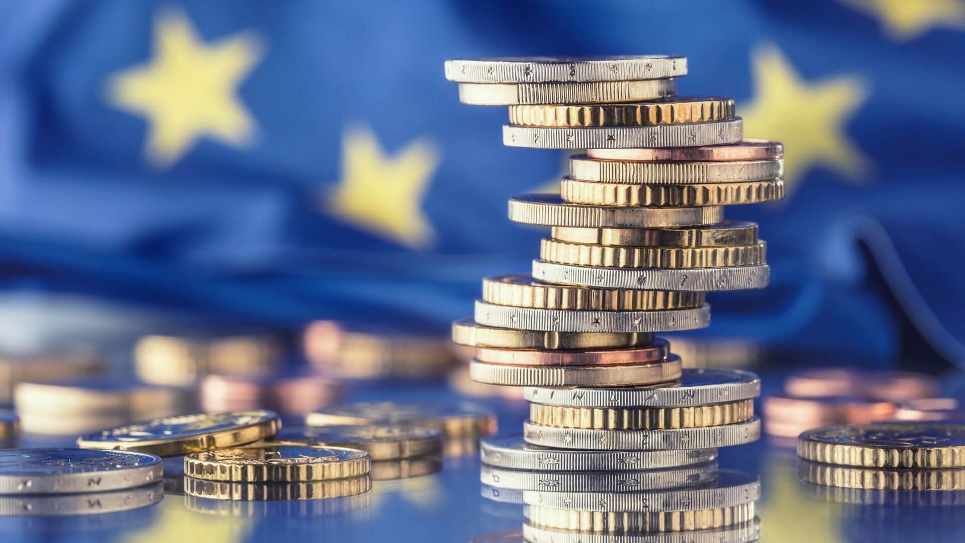 Pile of Euro coins stacked in front of European Union flag