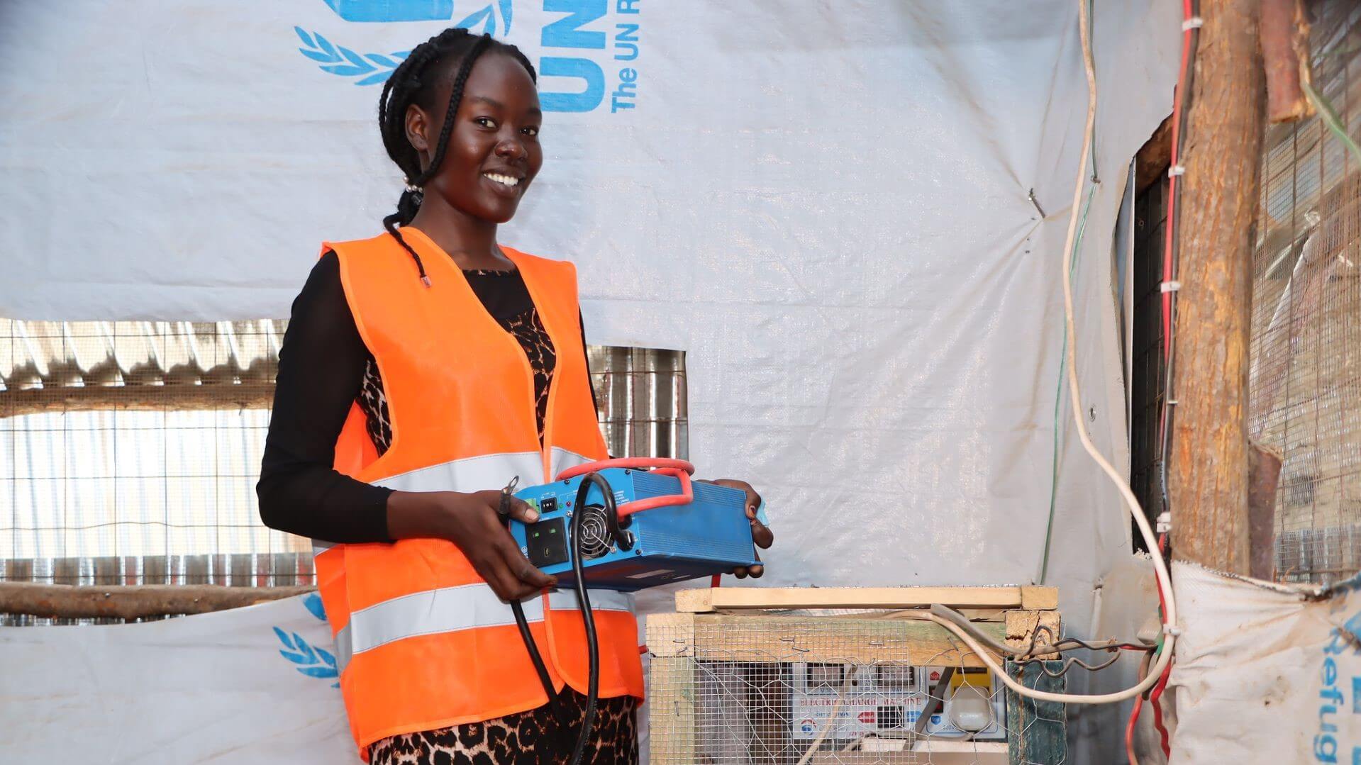Young women in basic room holding WiFi equipment connected to solar power