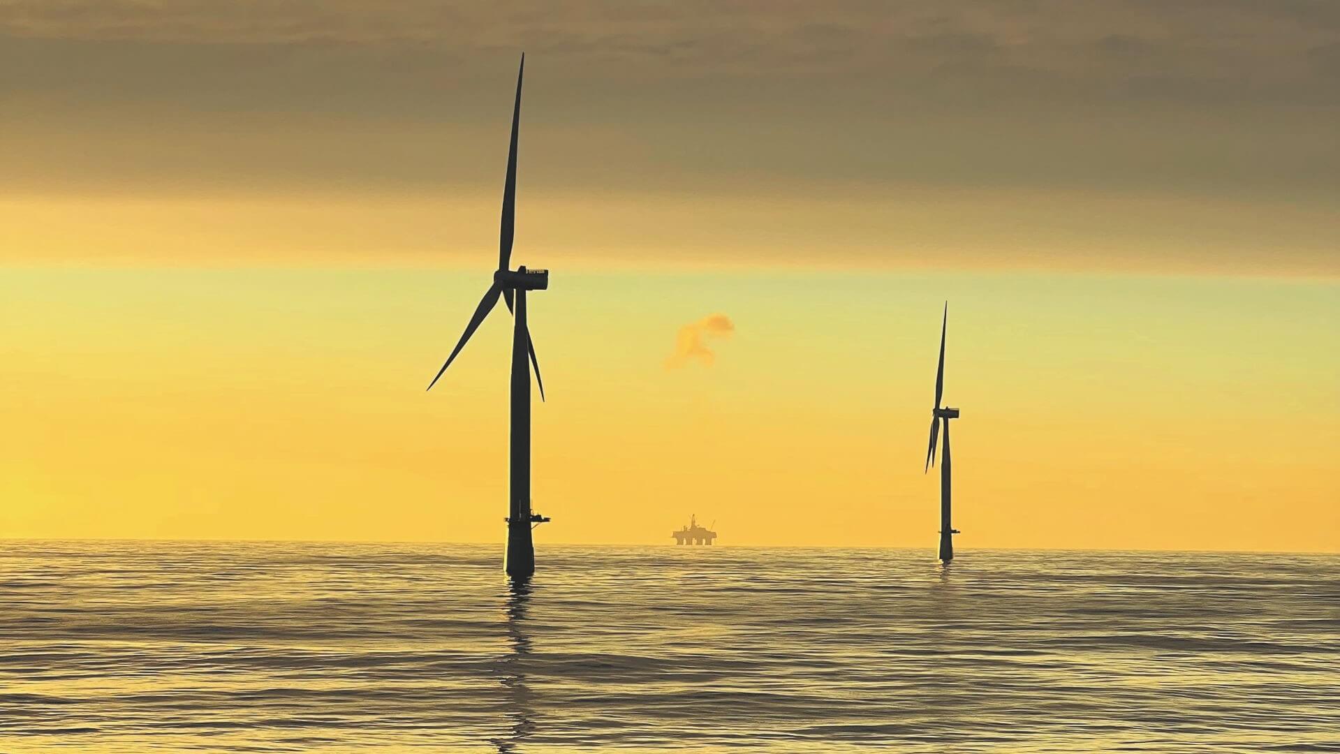 Offshore wind turbines with oil and gas platform in background