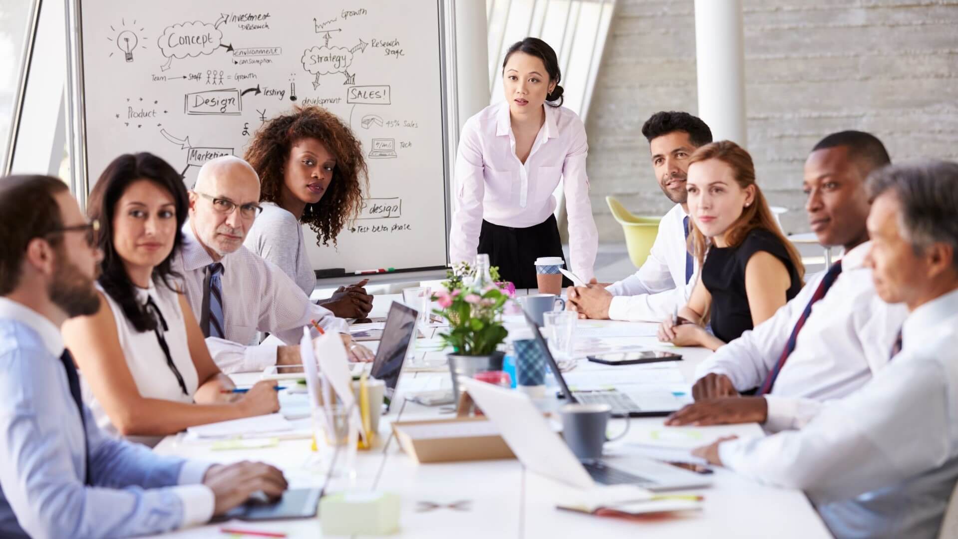 People sat around a table with woman leading a business meeting 