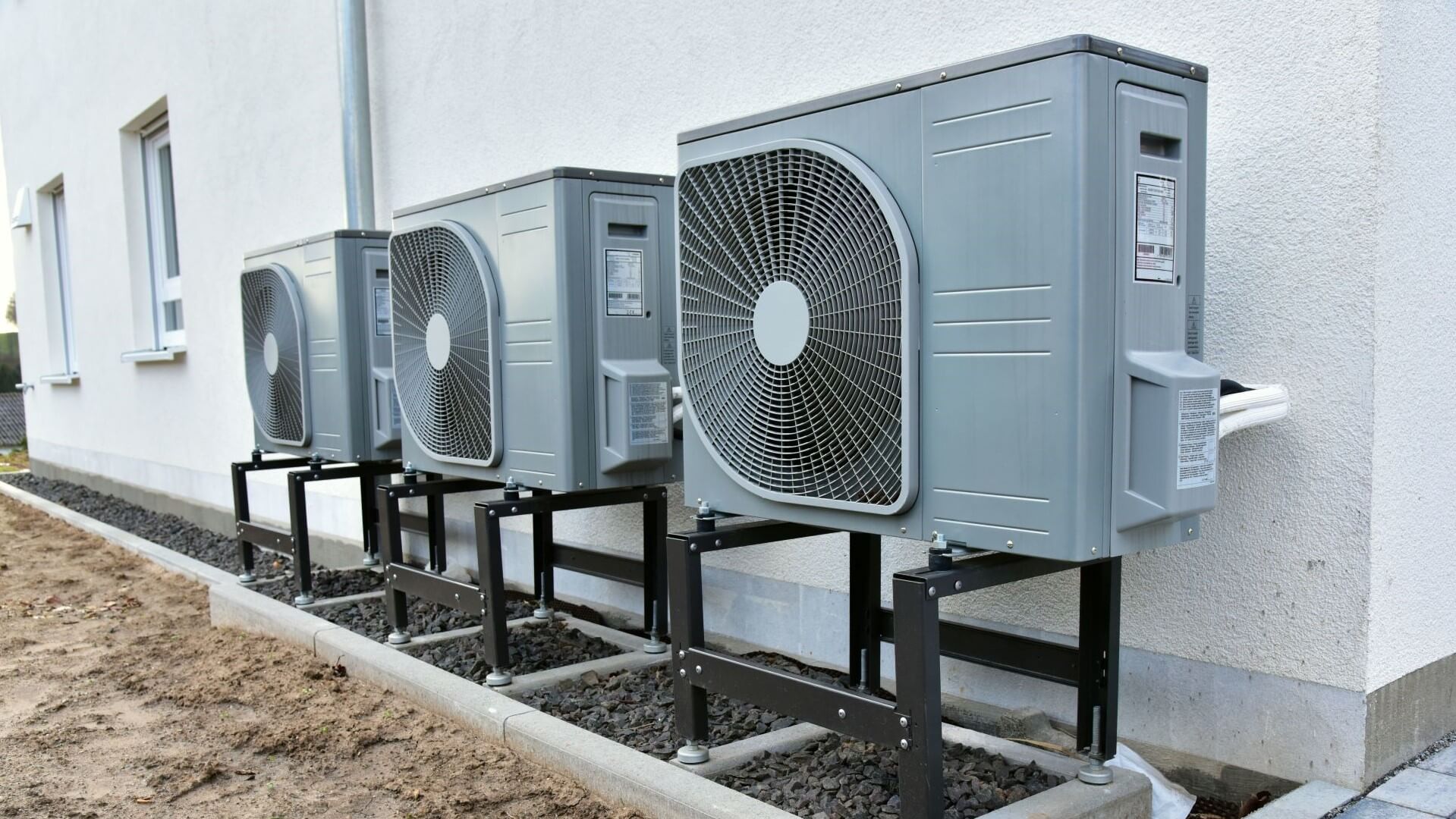 Row of three heat pump units on outside of a building
