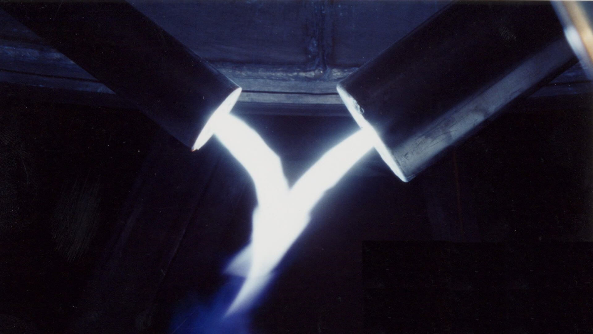 Close up of two plasma torches producing bright white 'flame' against dark backdrop