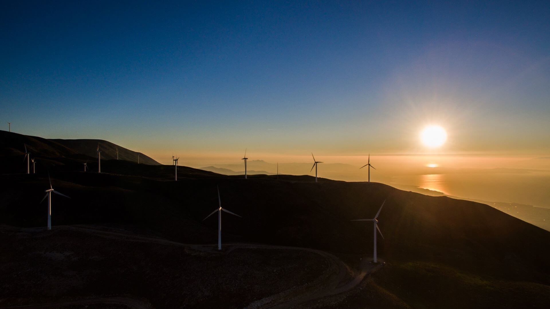 Wind turbines on a mountain near sea at sunset