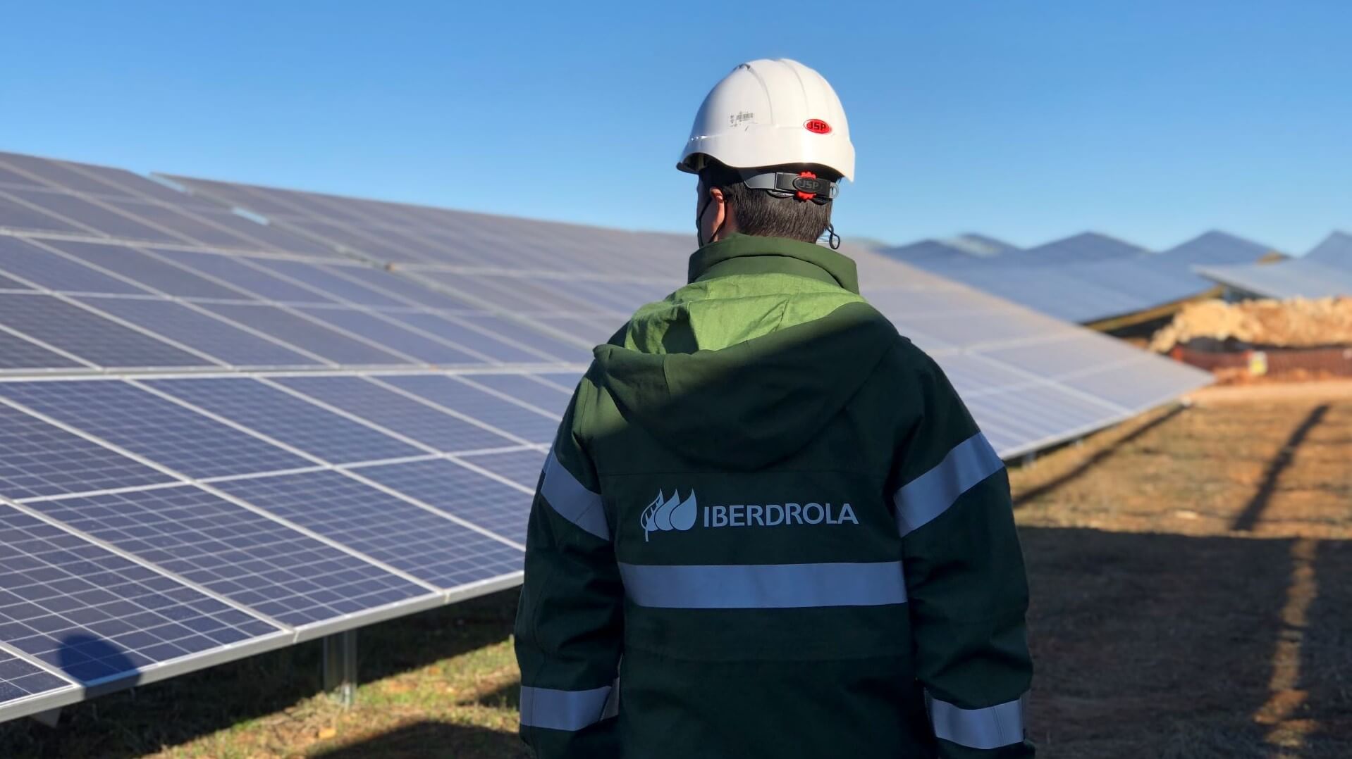 Engineer wearing hard hat, standing by solar panels in solar farm