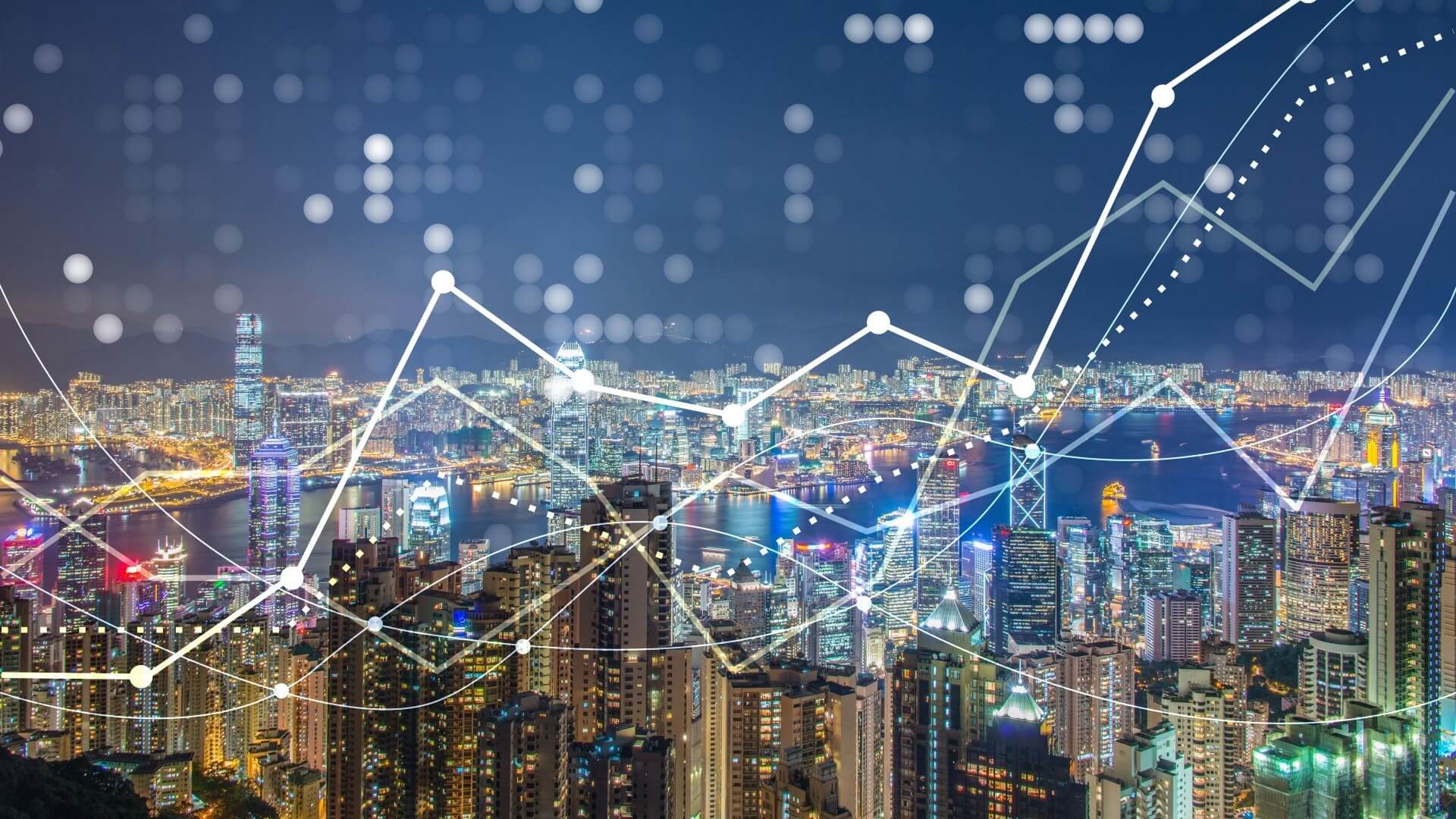 Graph lines showing business trends rising over lit up city skyline at night