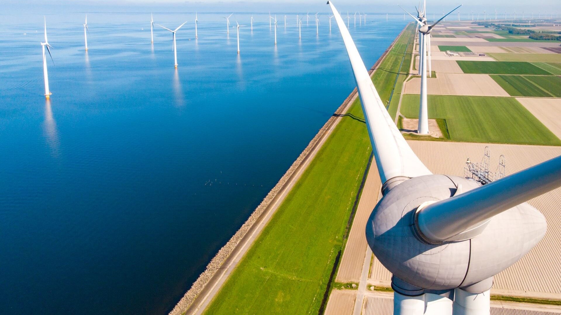 Aerial view of offshore wind turbines and onshore wind turbines along coast line