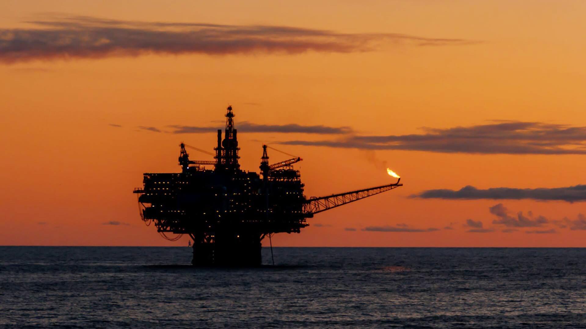 Offshore platform with gas flare at sunset
