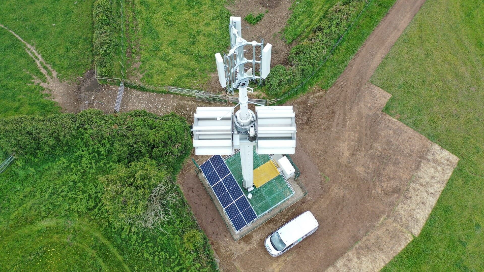 Overhead birds eye view of small wind turnbine with solar panels and battery storage at base