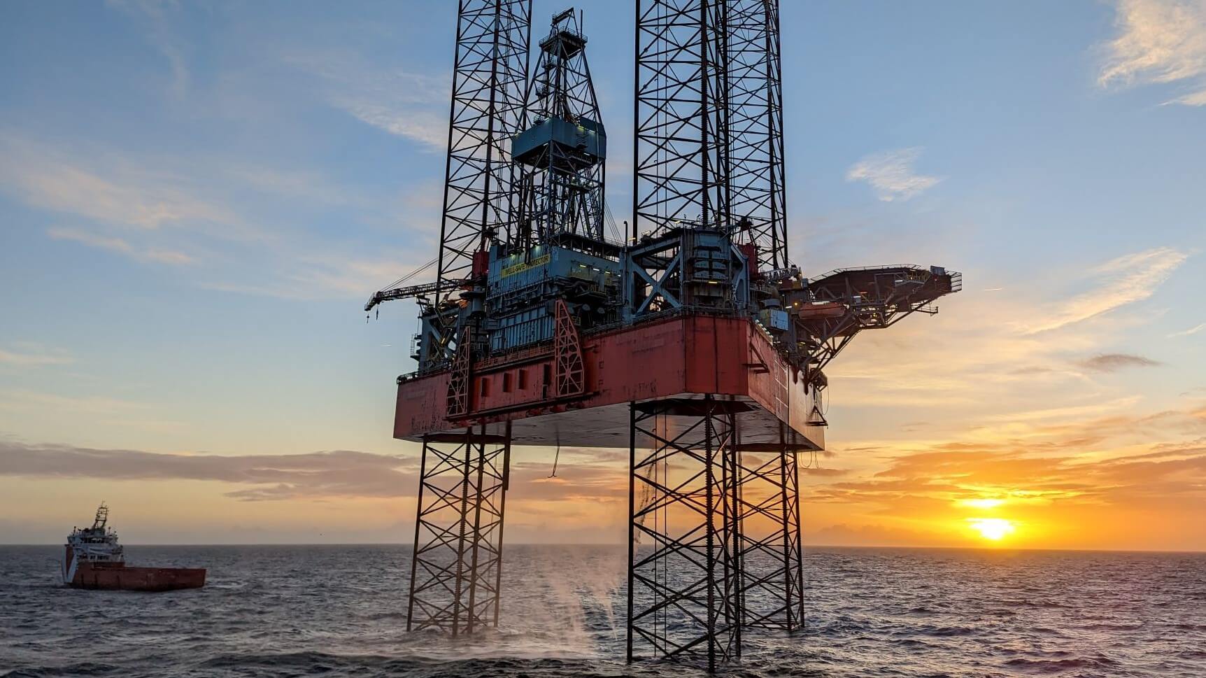 Jack-up rig in calm sea with sunset behind