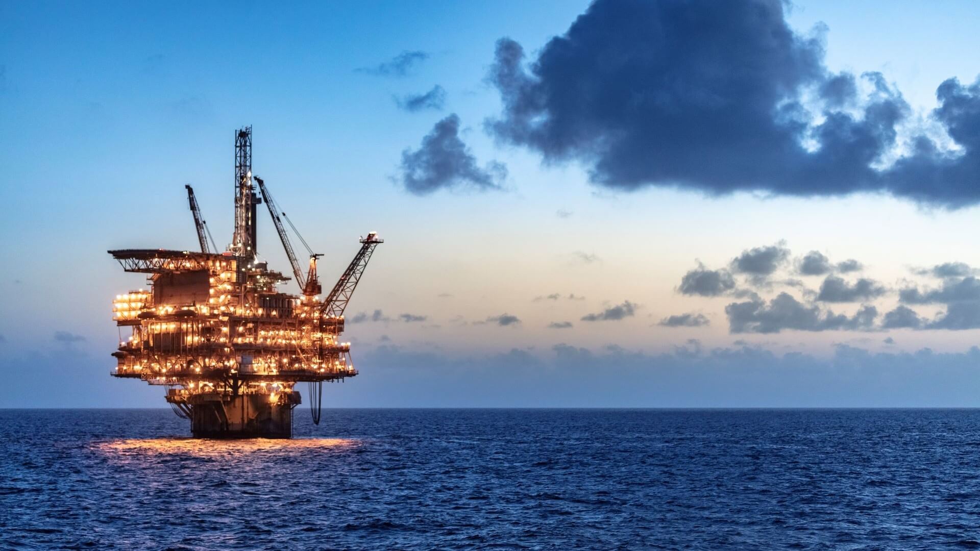 Oil and gas platform lit up at night in dark blue sea