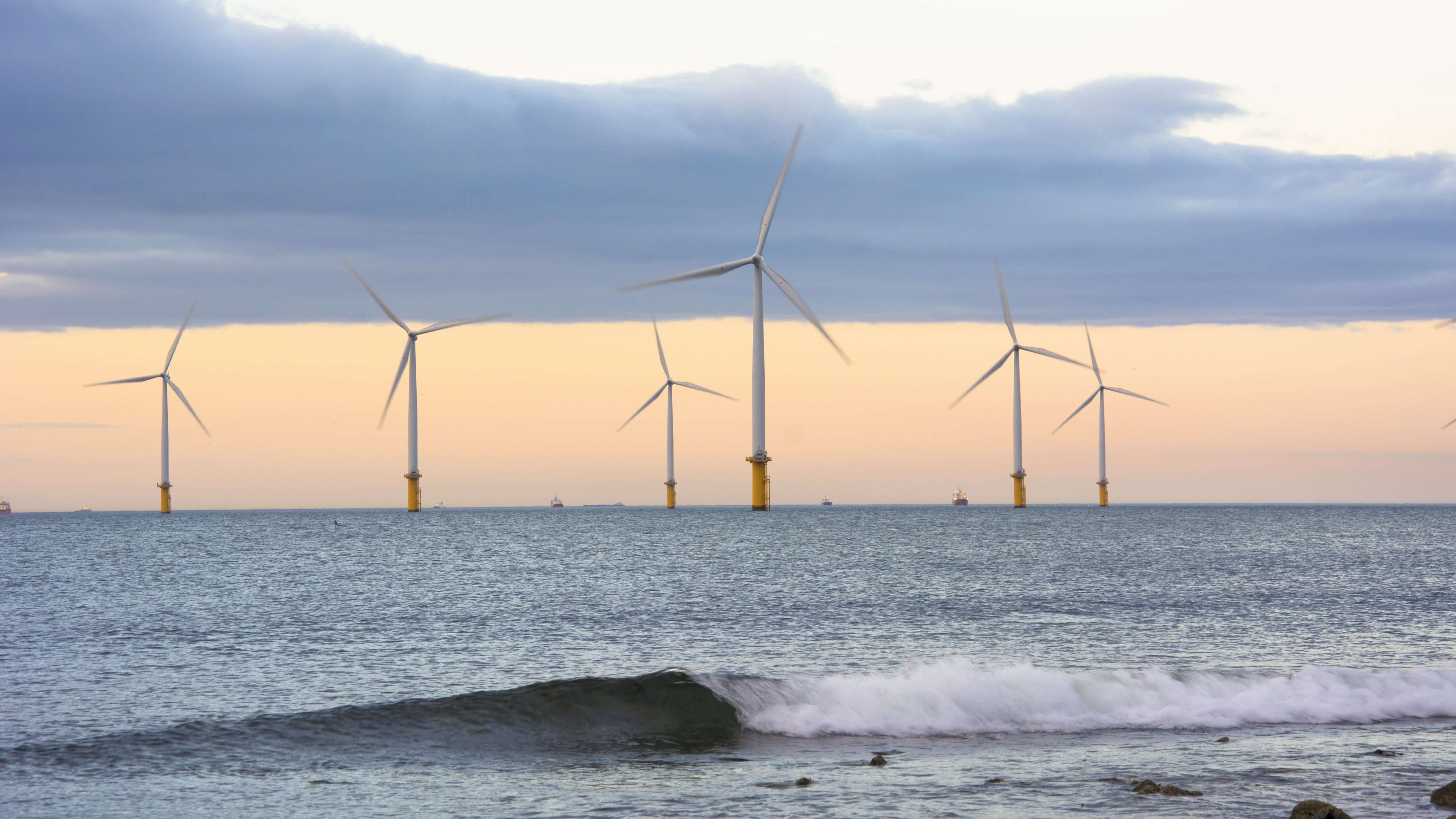 Offshore wind farm at sea with breaking waves in foreground