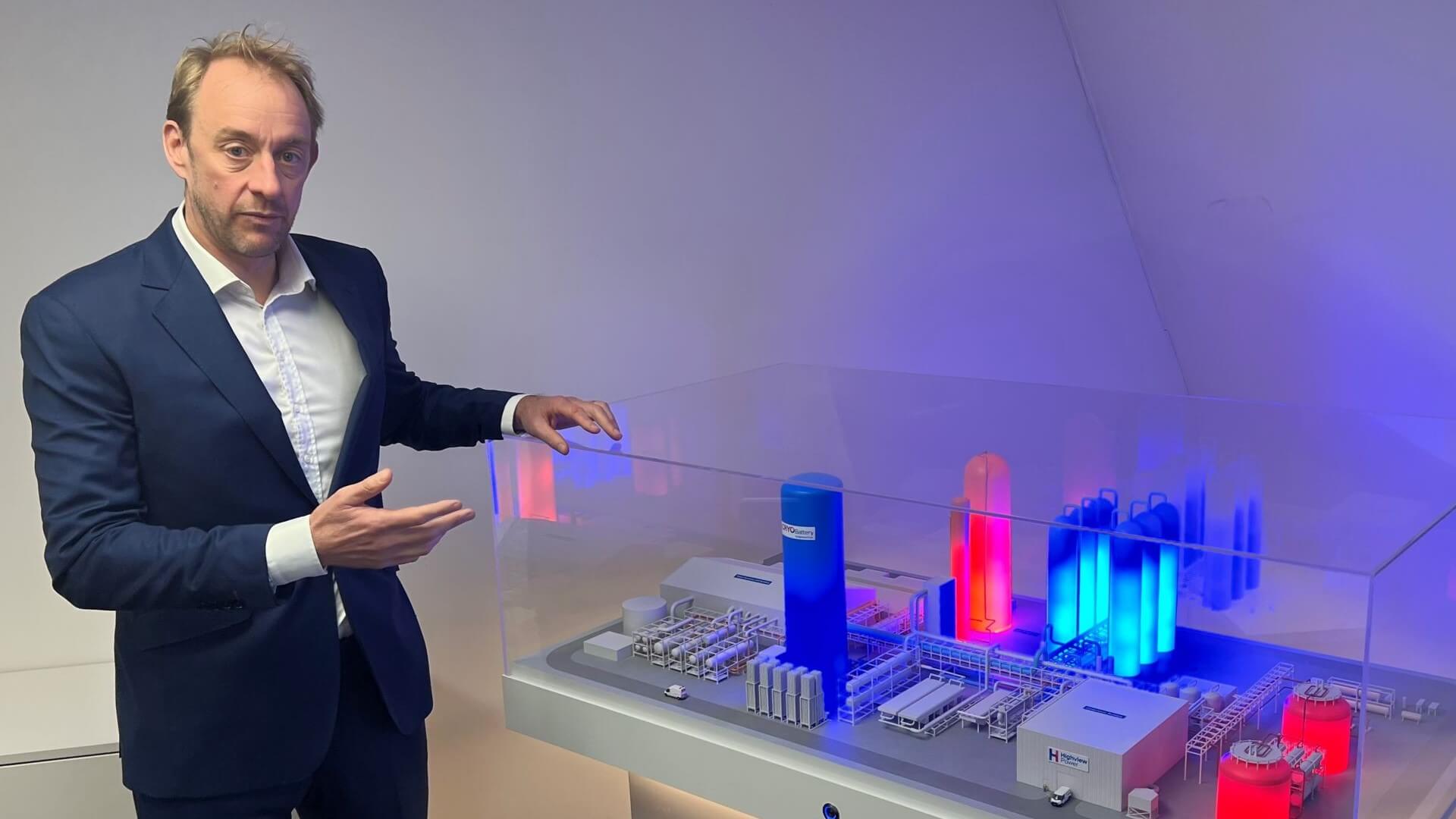Photo of Richard Butland, CEO, Highview Power, standing next to model of buildings lit up in red and blue