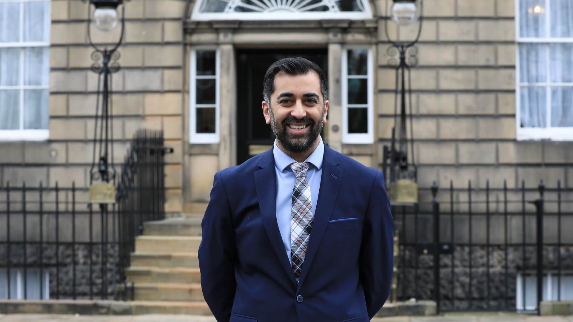 Photo of Humza Yousaf, First Minister of Scotland, standing outside government office
