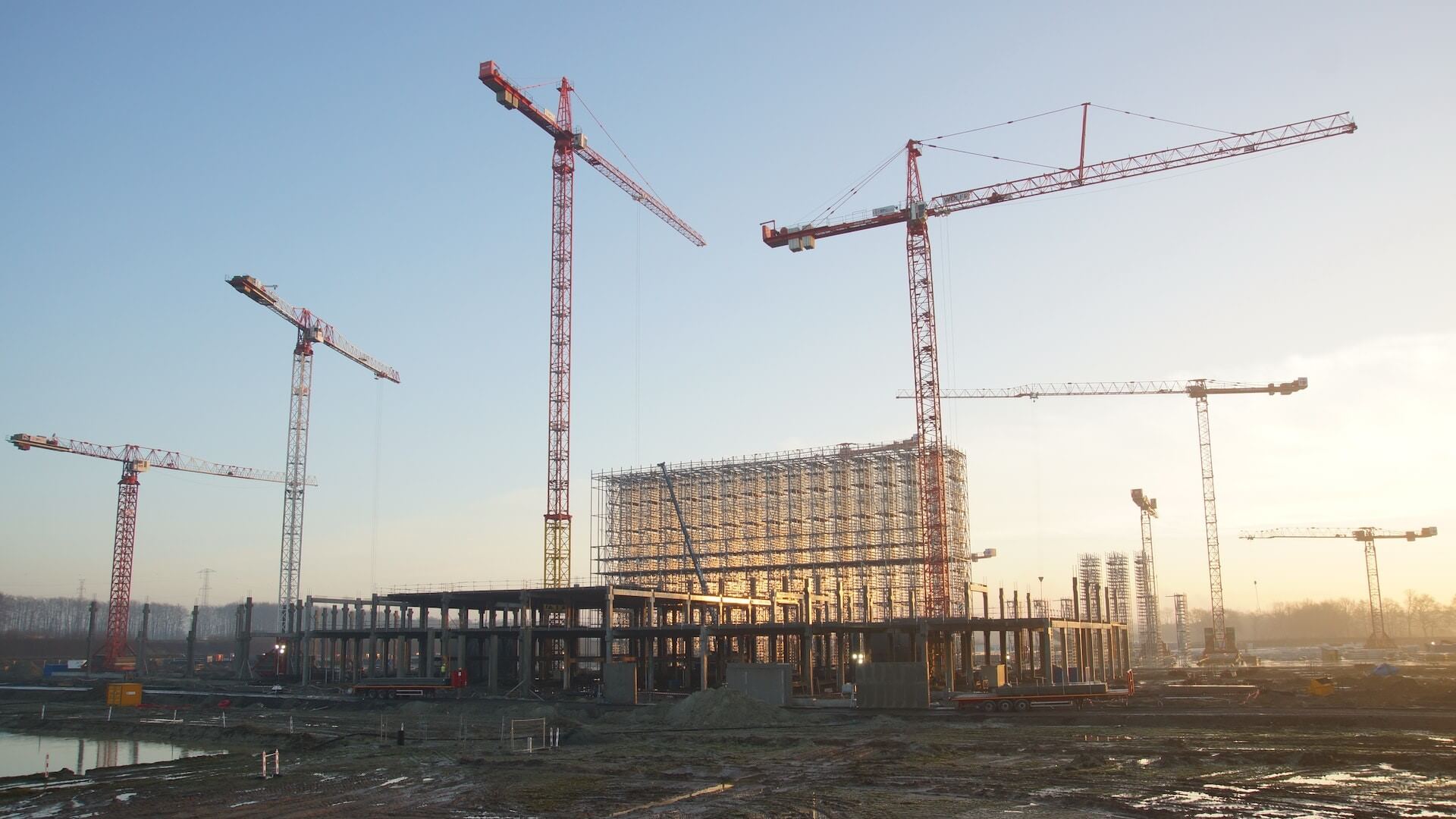 Large cranes constructing building, set against sky