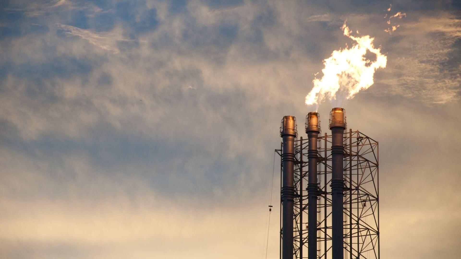 Close up of flaming gas flares set against cloudy sky