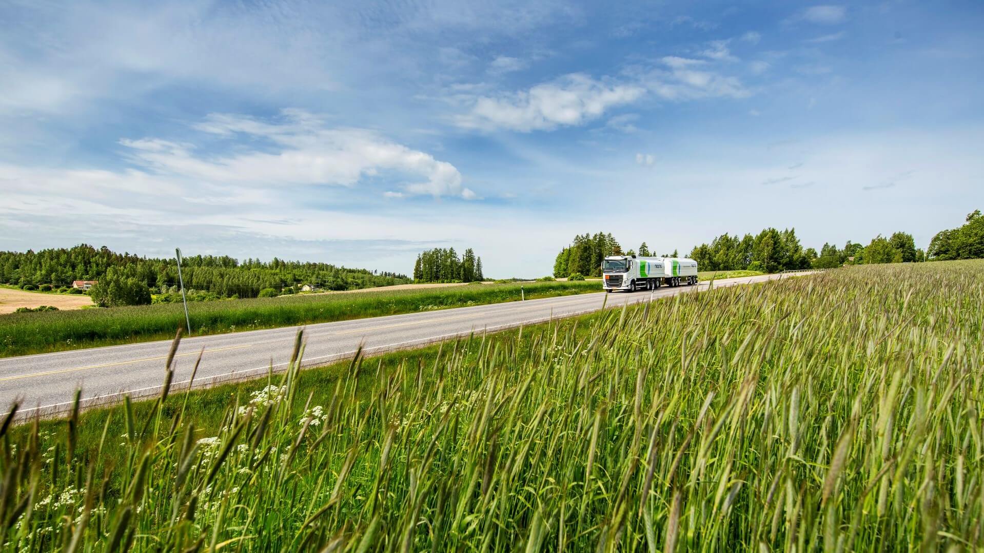 Biofuels truck on road between fields filled with crops