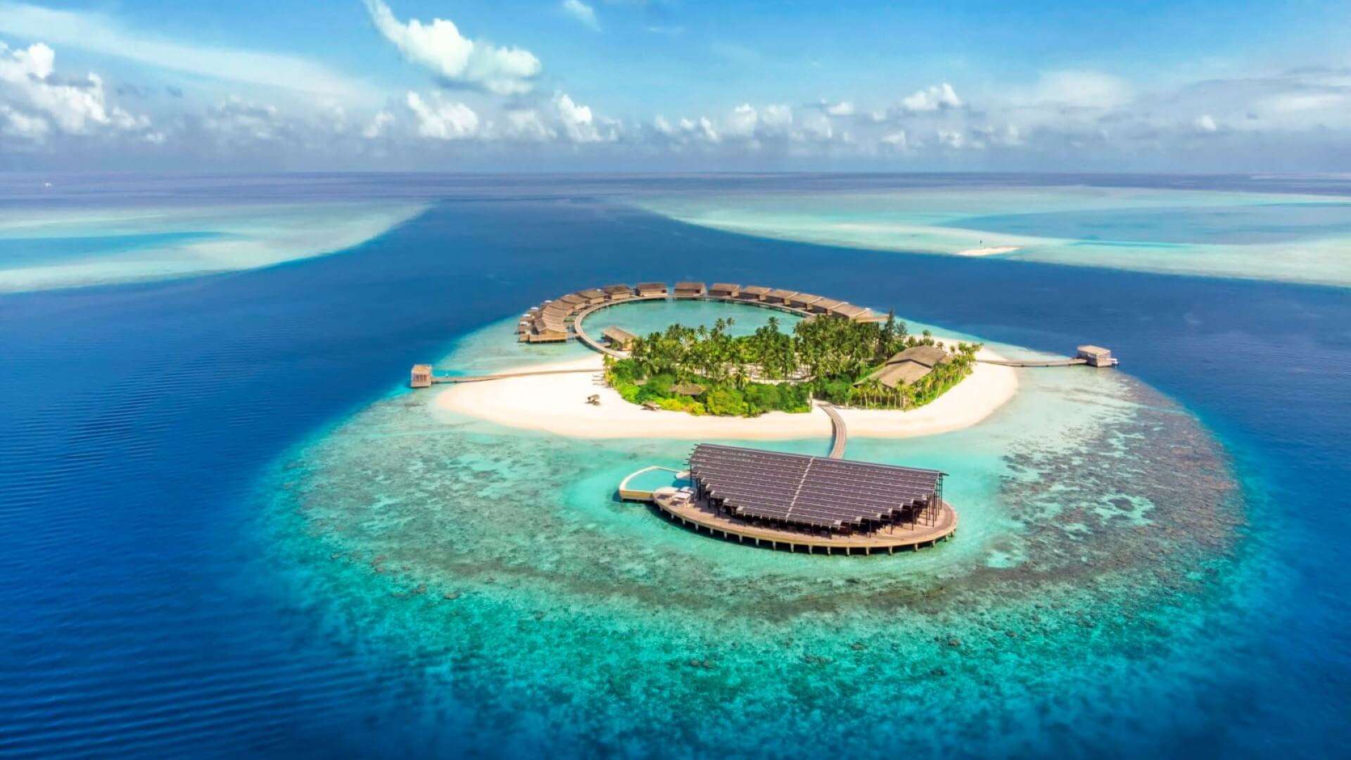 Aerial view of small island with sandy beaches and floating solar resort set in blue sea