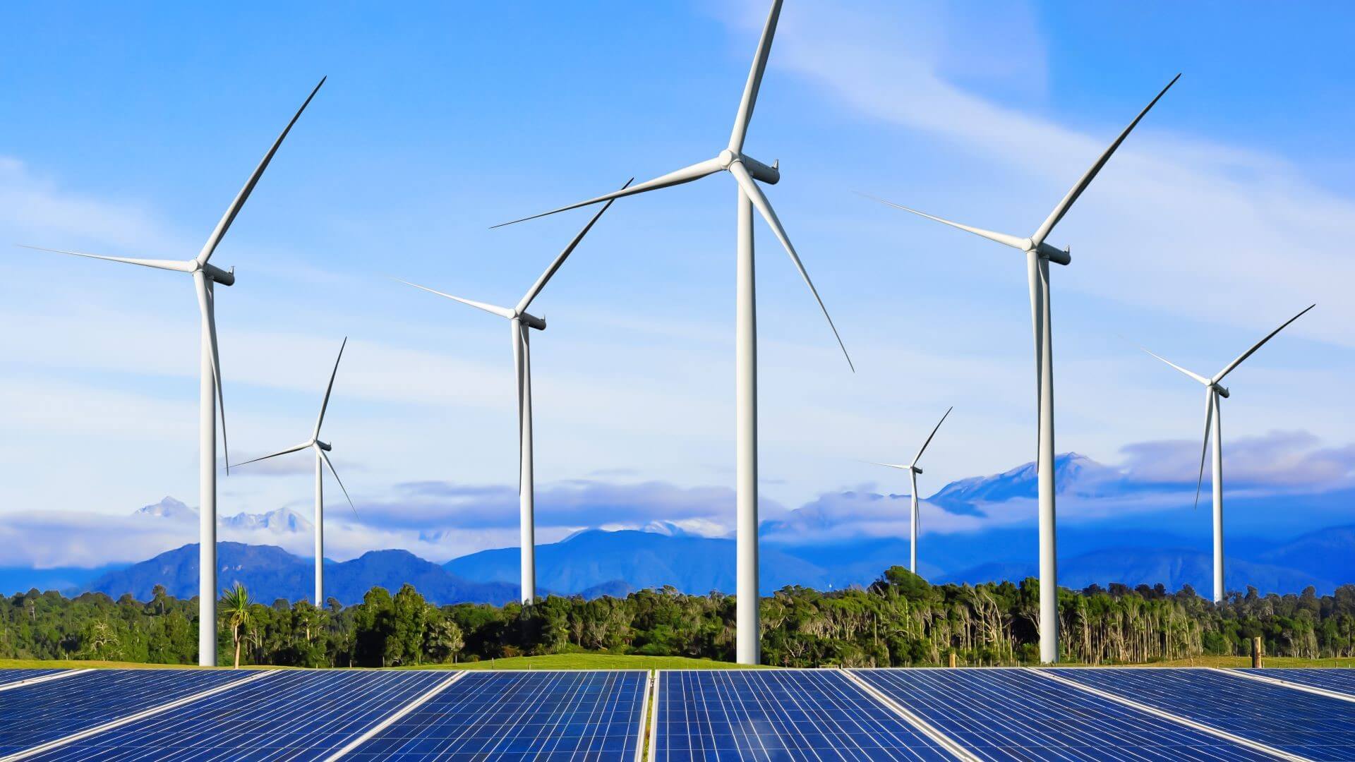 Wind turbines and solar panels against mountains and blue sky