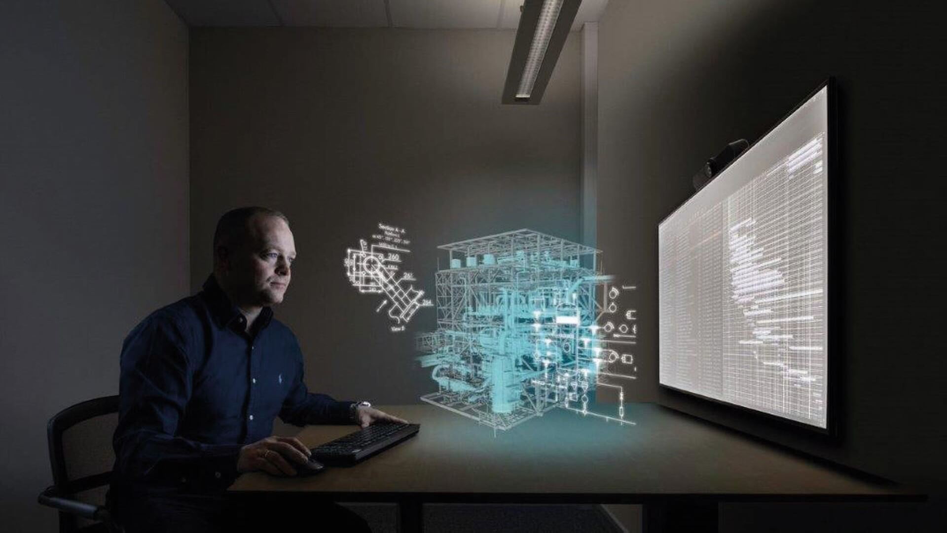 Man sitting in dark room with 3D computer generated digital twin schematic of installation floating in front of him