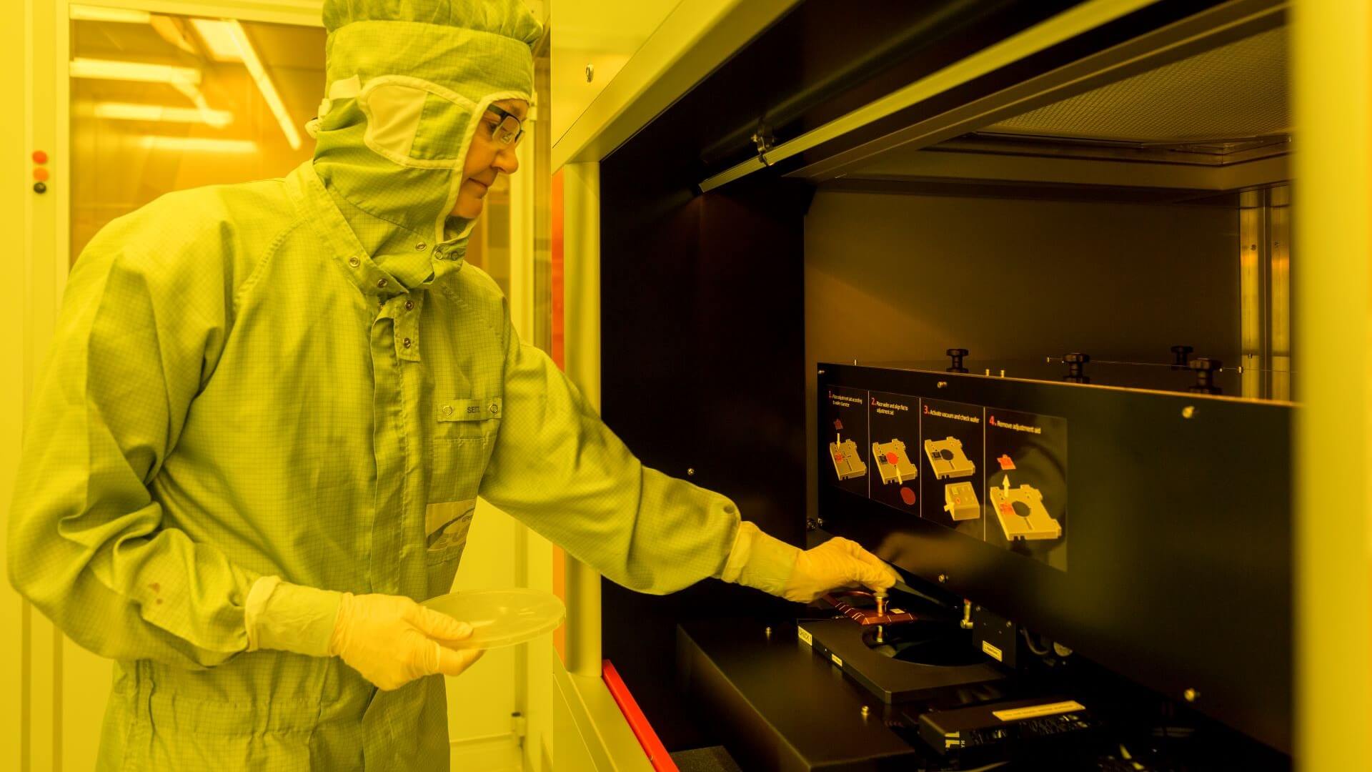 Lab technician in paper coveralls and global operating lab equipment under yellow lighting