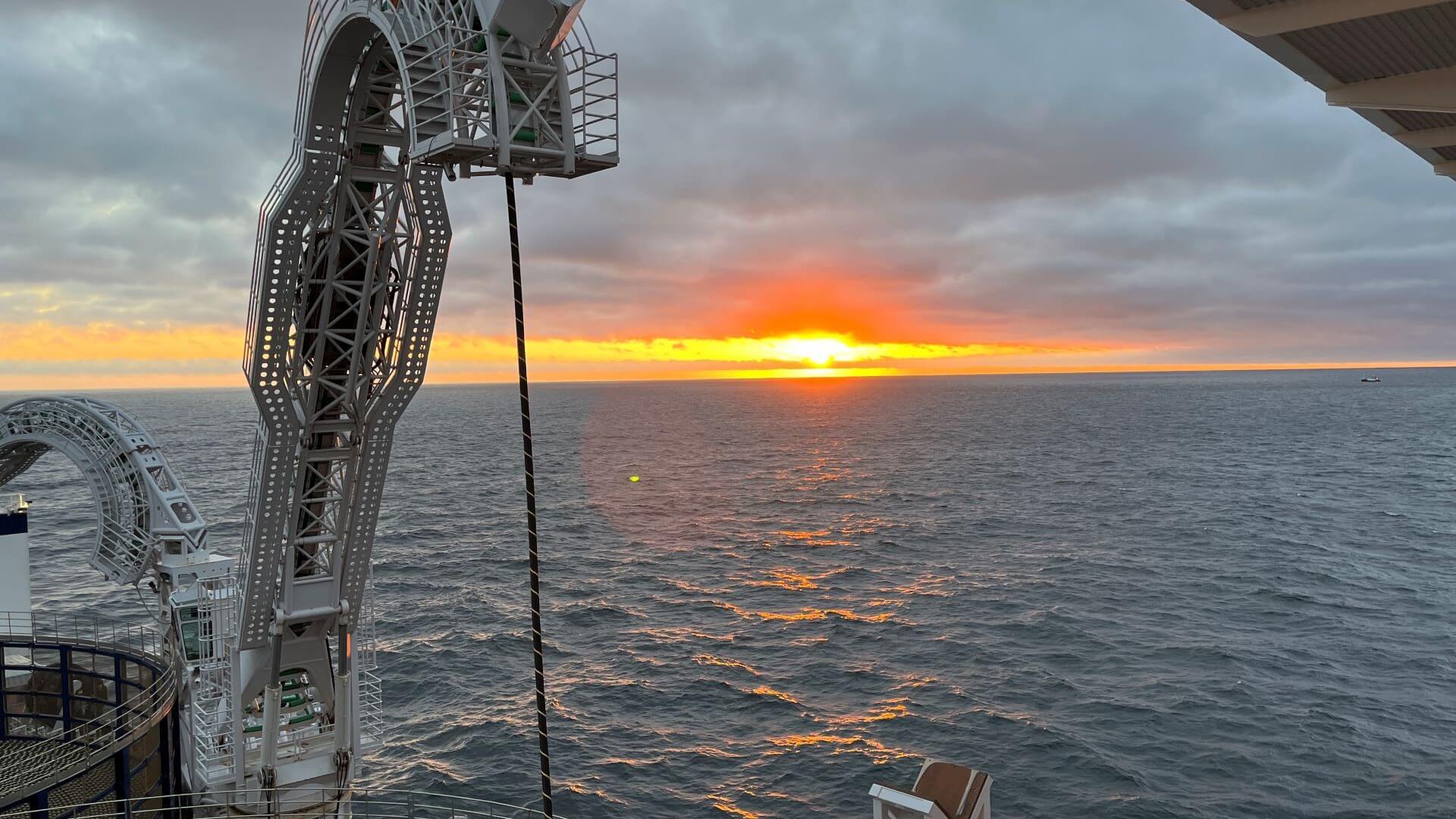 Close up of cable being run from back of cable laying vessel set against sunset