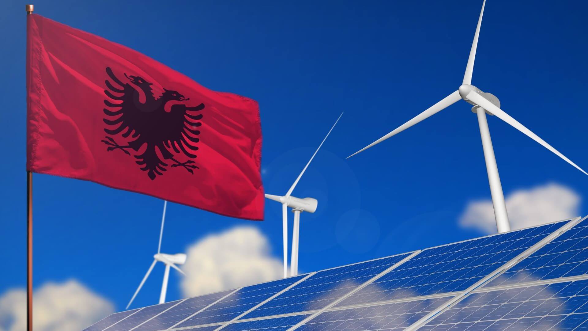 Albania flag flying next to wind turbines and solar panels
