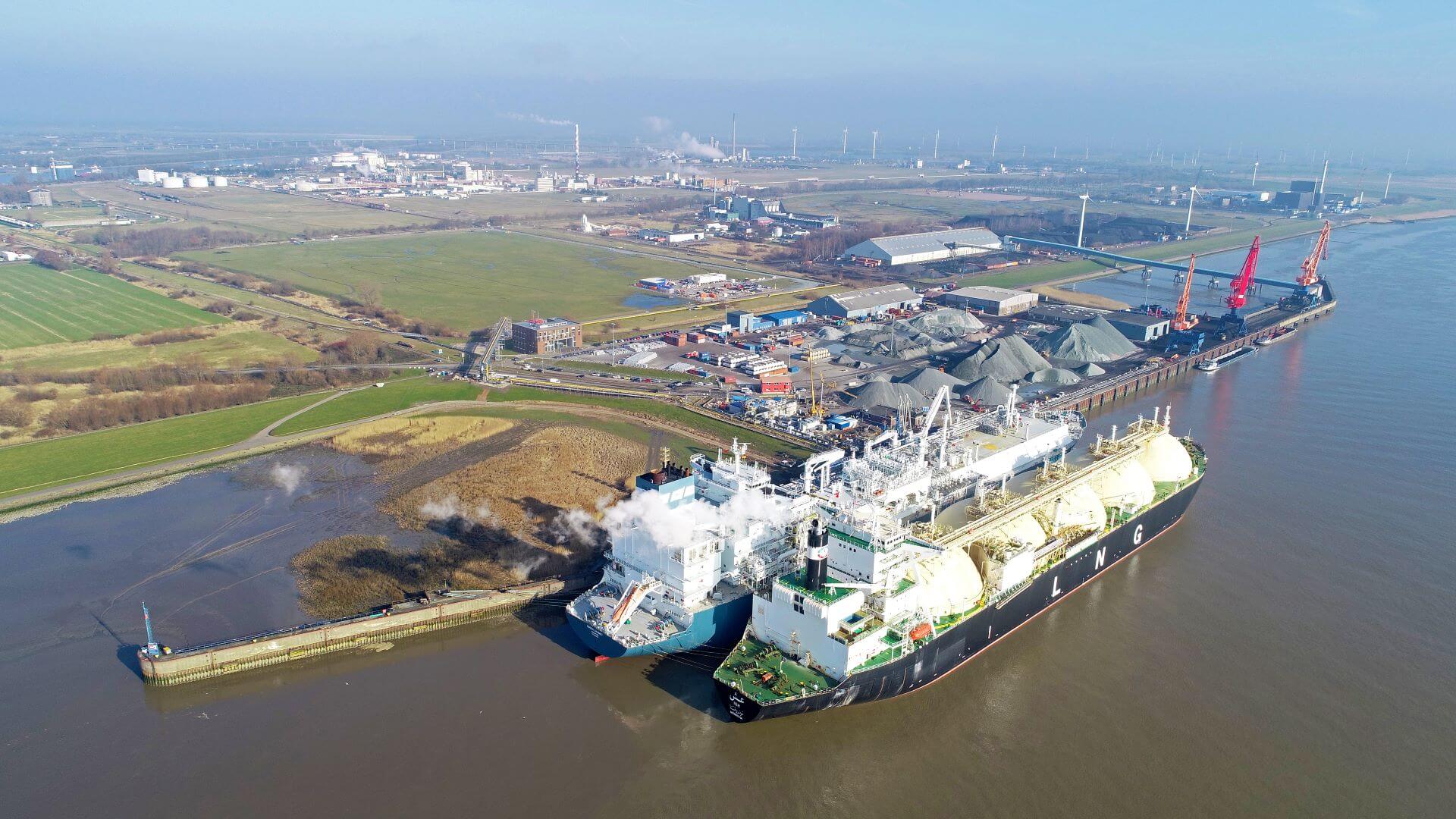 Two large ships with half sphere LNG containment tanks docked alongside LNG terminal