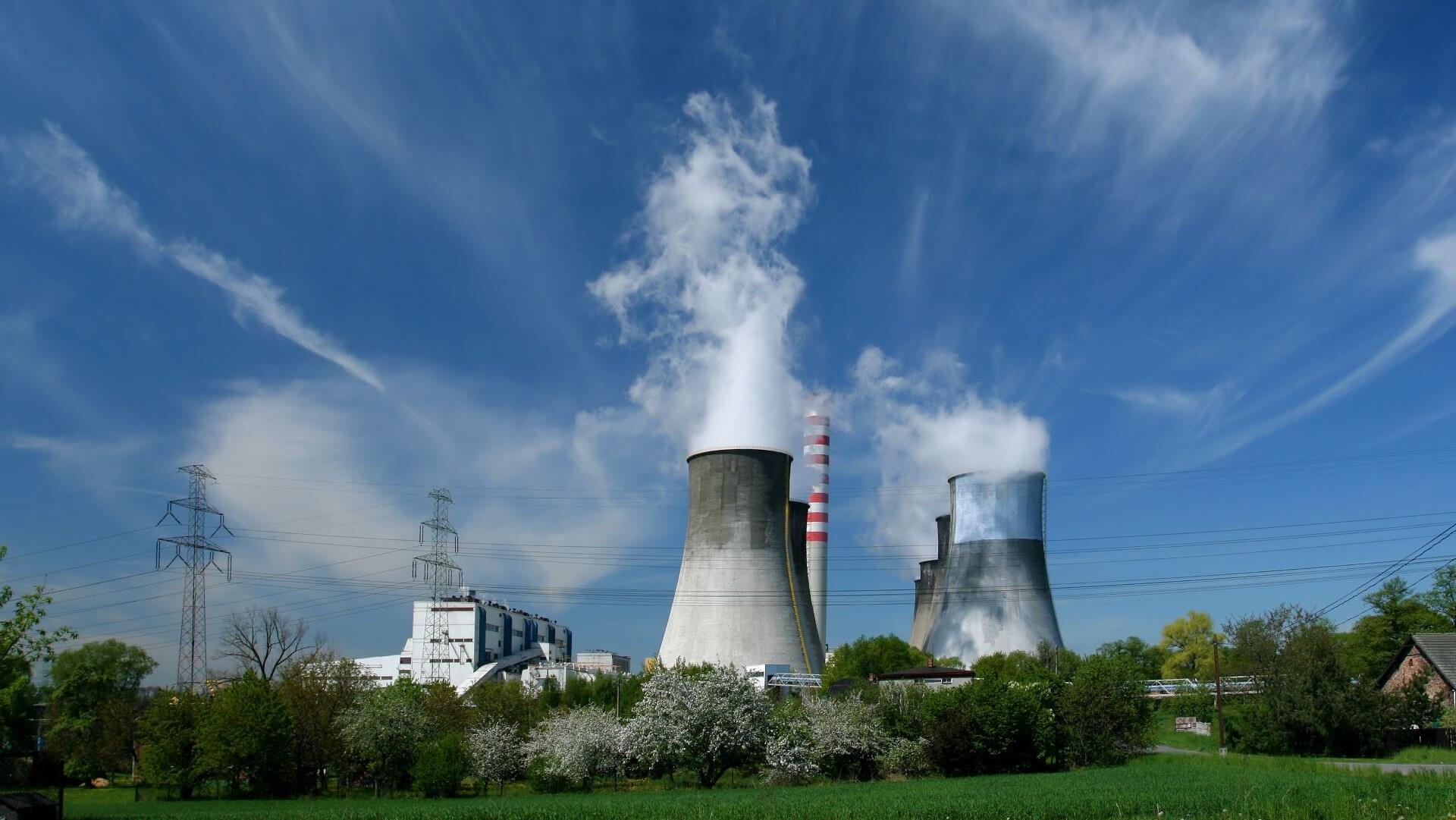 Large chimney towers of a coal power plant venting steam into blue sky