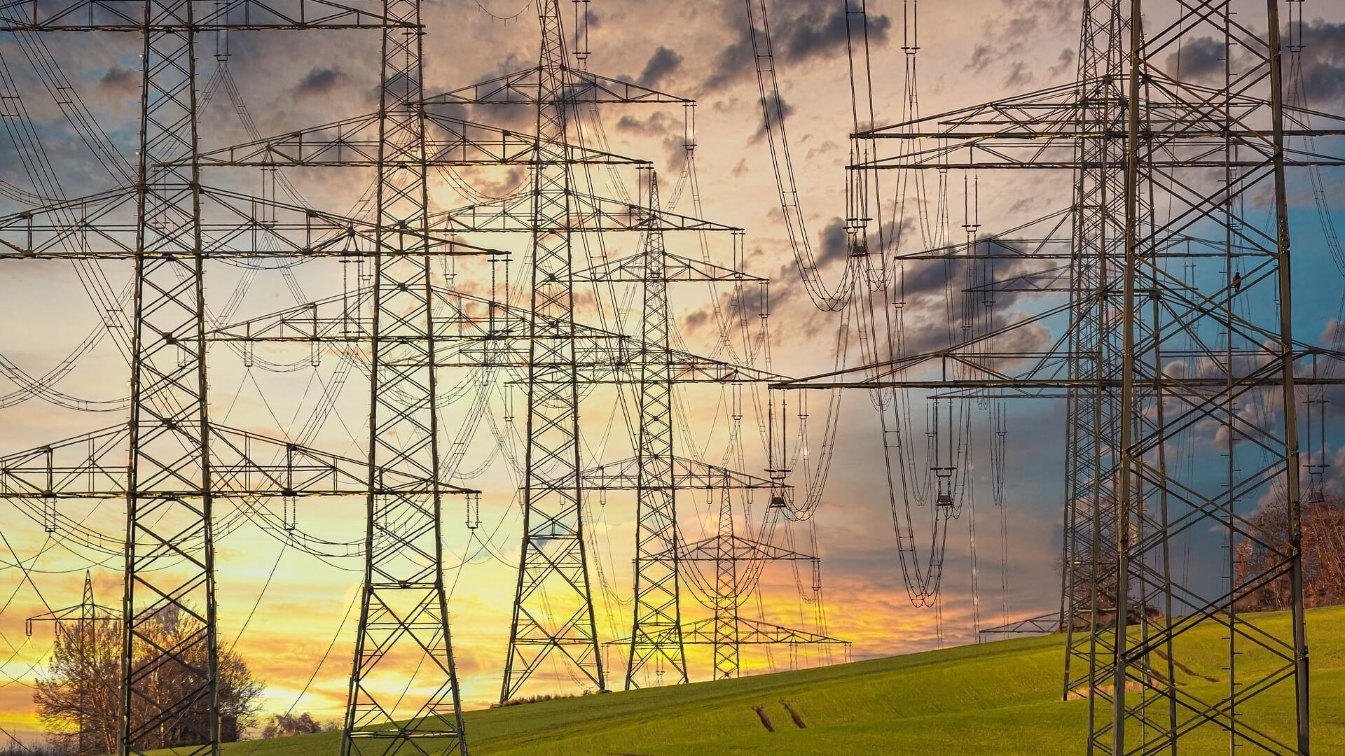 Electricity pylons silhoutted against sunset sky