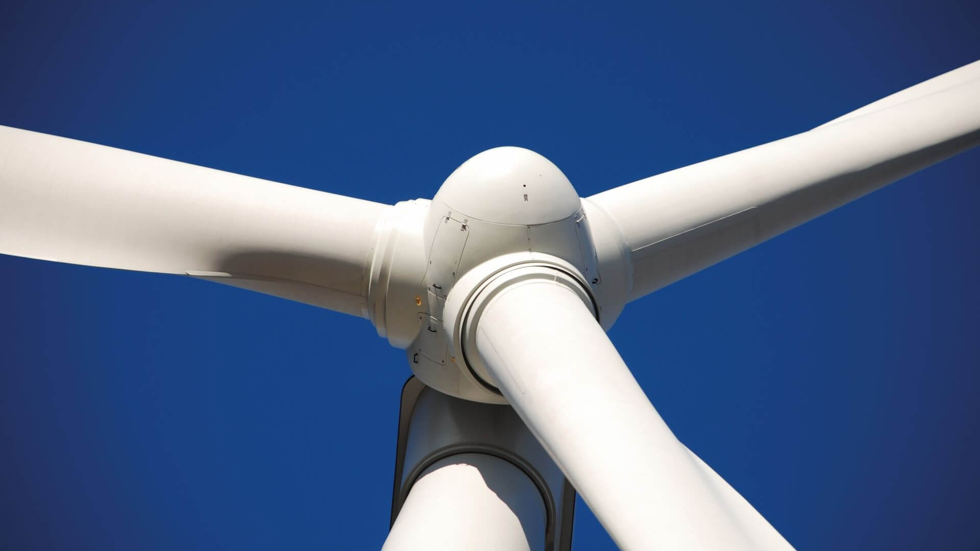 Close up view of wind turbine blades against a blue sky
