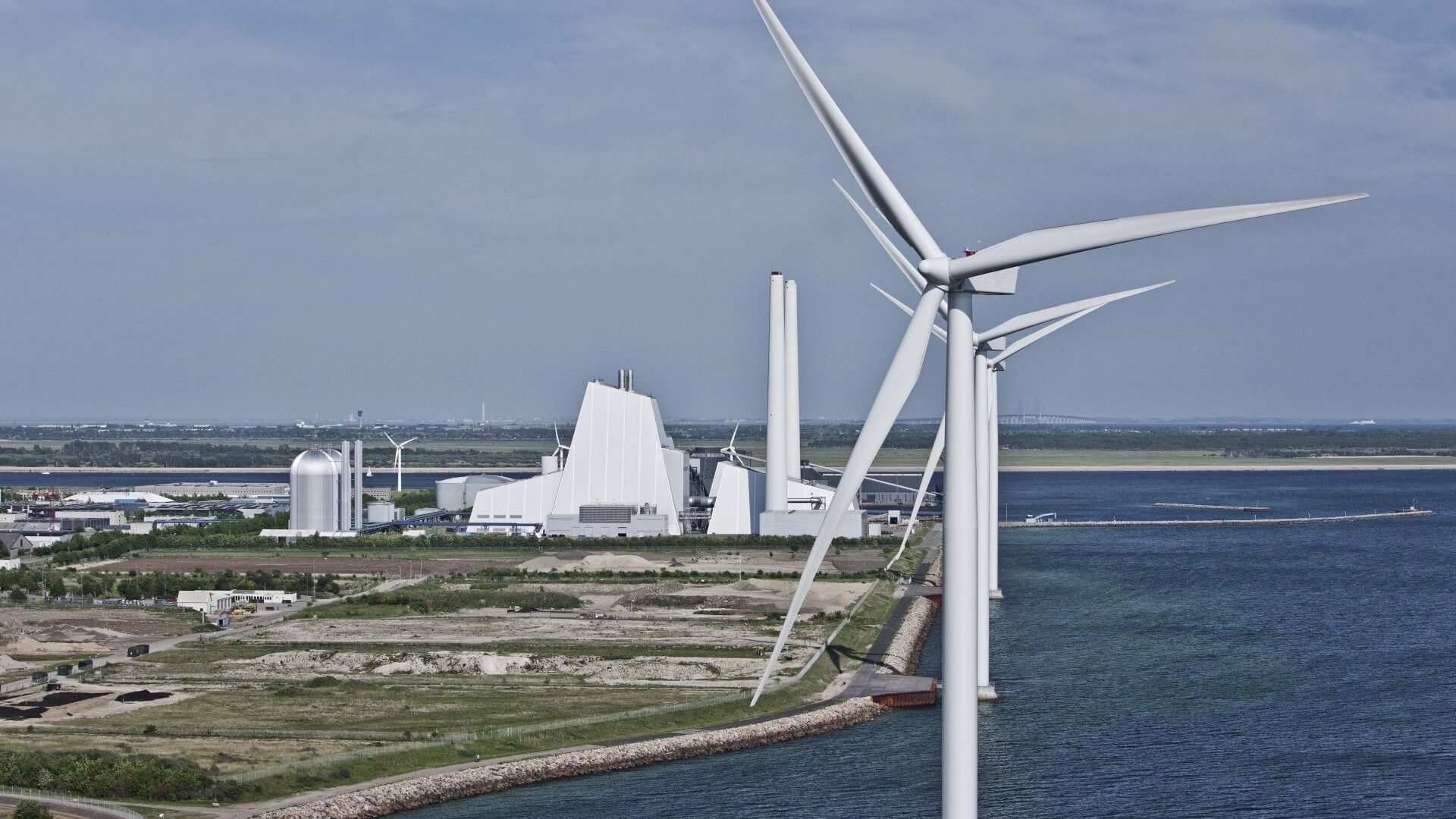 Power station in background, with wind turbines in the foreground