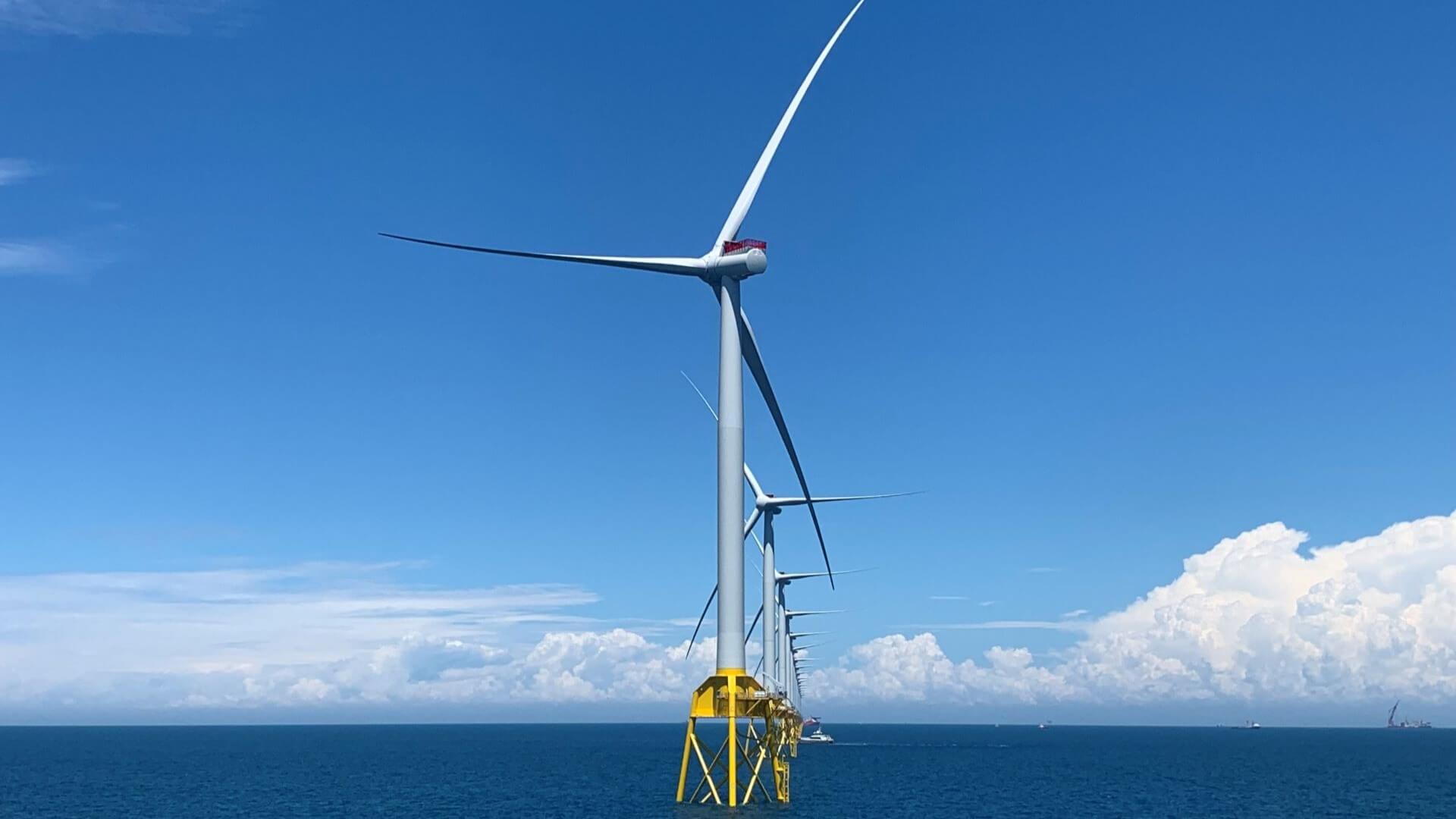 Floating offshore wind turbine in blue sea with blue sky and fluffy white clouds